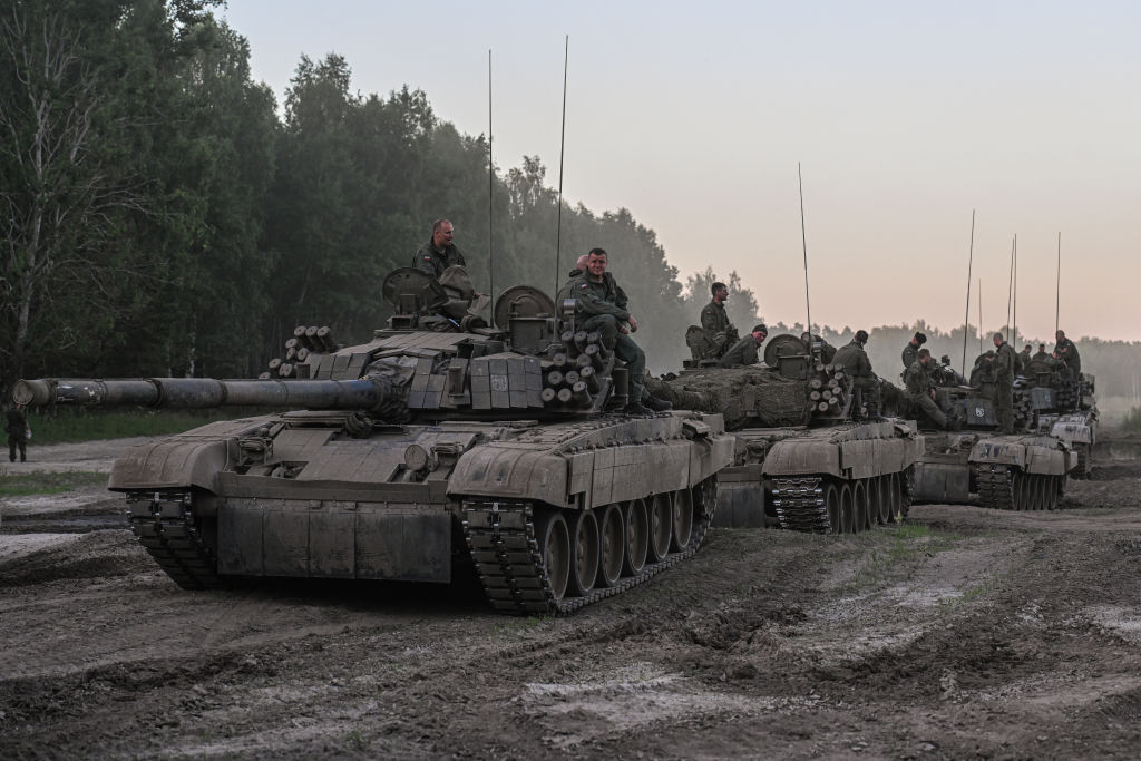 Polish soldiers stand on tanks after a training demonstration with the NATO multinational battle group eFPon at the Orzysz training ground on July 3, 2022 in Orzysz, Poland. (Omar Marques—Getty Images)