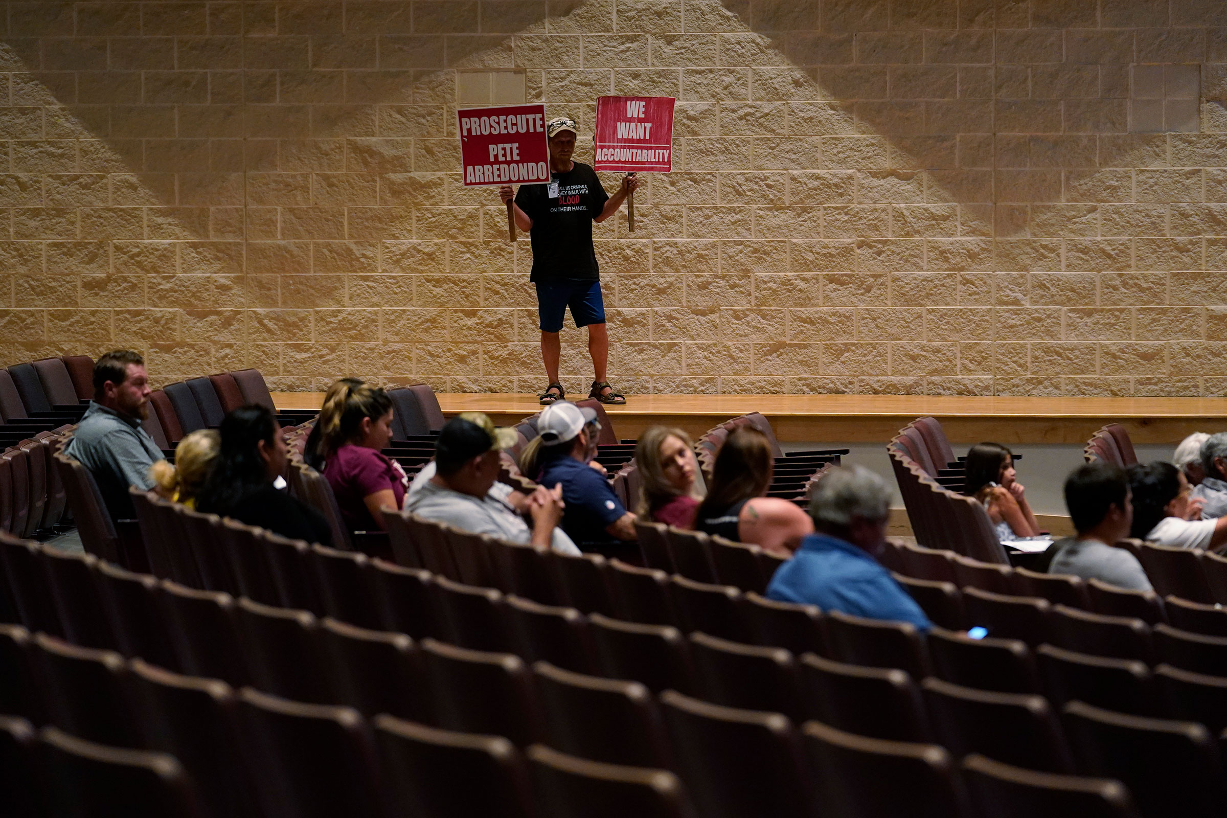 Michael Brown holds protest signs during a special school board meeting in Uvalde to address concerns over last month's shootings at Robb Elementary School, on July 18. (Eric Gay—AP)