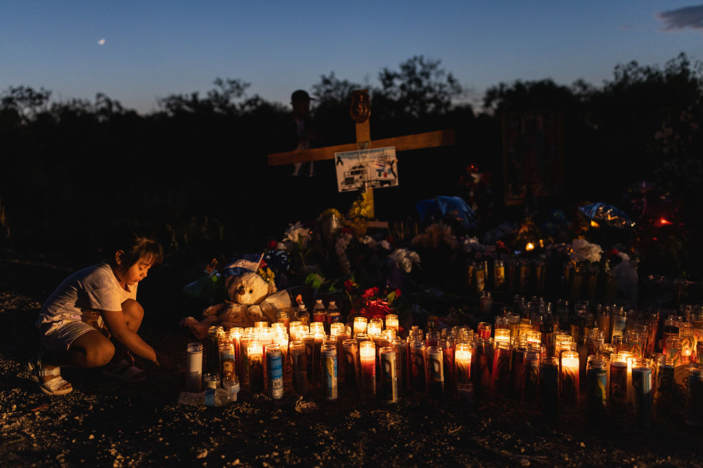 People gather at a makeshift memorial which has been erected at the site where 53 migrants died on June 30, 2022 in San Antonio, Texas. (Jordan Vonderhaar—Getty Images)
