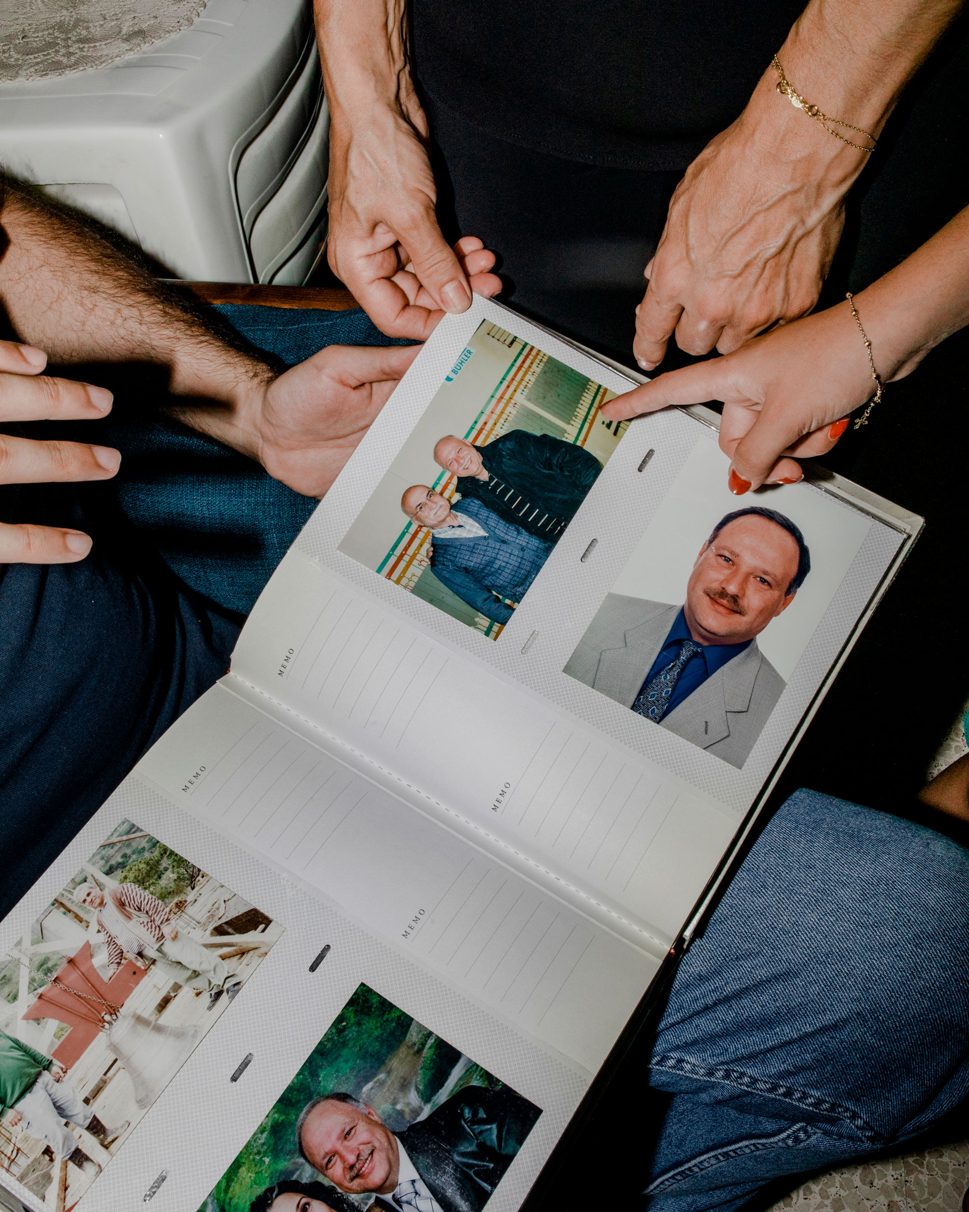 Elie, Ibtissam and Tatiana Hasrouty look at a family album with photographs of Ghassan working in the silos at Beirut’s port, where he worked and passed away.