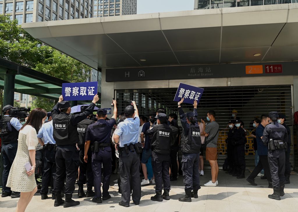 Police officers look at people gathering at the Evergrande headquarters in Shenzhen, southeastern China on September 16, 2021, as the Chinese property giant said it is facing "unprecedented difficulties" but denied rumors that it is about to go under. (Noel Celis—AFP/Getty Images)