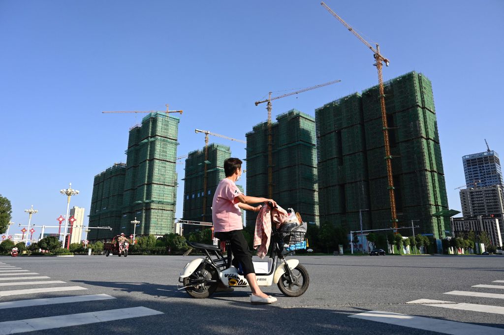 A woman rides a scooter past the construction site of an Evergrande housing complex in Zhumadian, central China's Henan province on September 14, 2021. (Jade Gao&mdash;AFP/Getty Images)
