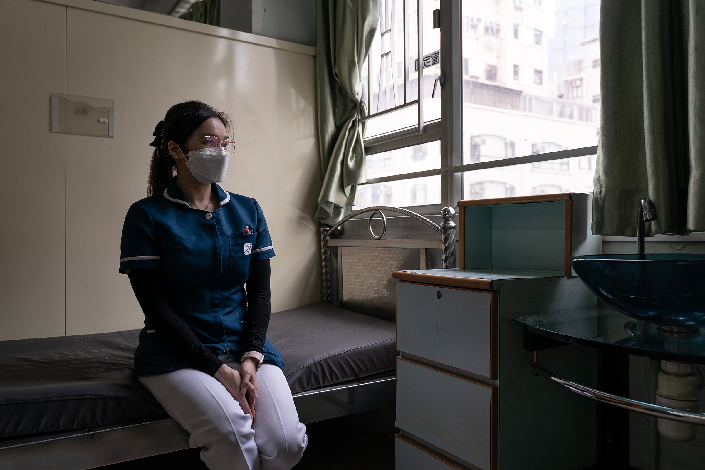 In Hong Kong's Yuen Long district, on May 6, 2022, Wong Wing-yan, a nurse at the Kei Tak (Tai Hang) Home for the Aged, sits on the bed of a resident she fondly called her godmother. The resident passed away during Hong Kong's last COVID-19 surge. (Anthony Kwan for TIME)