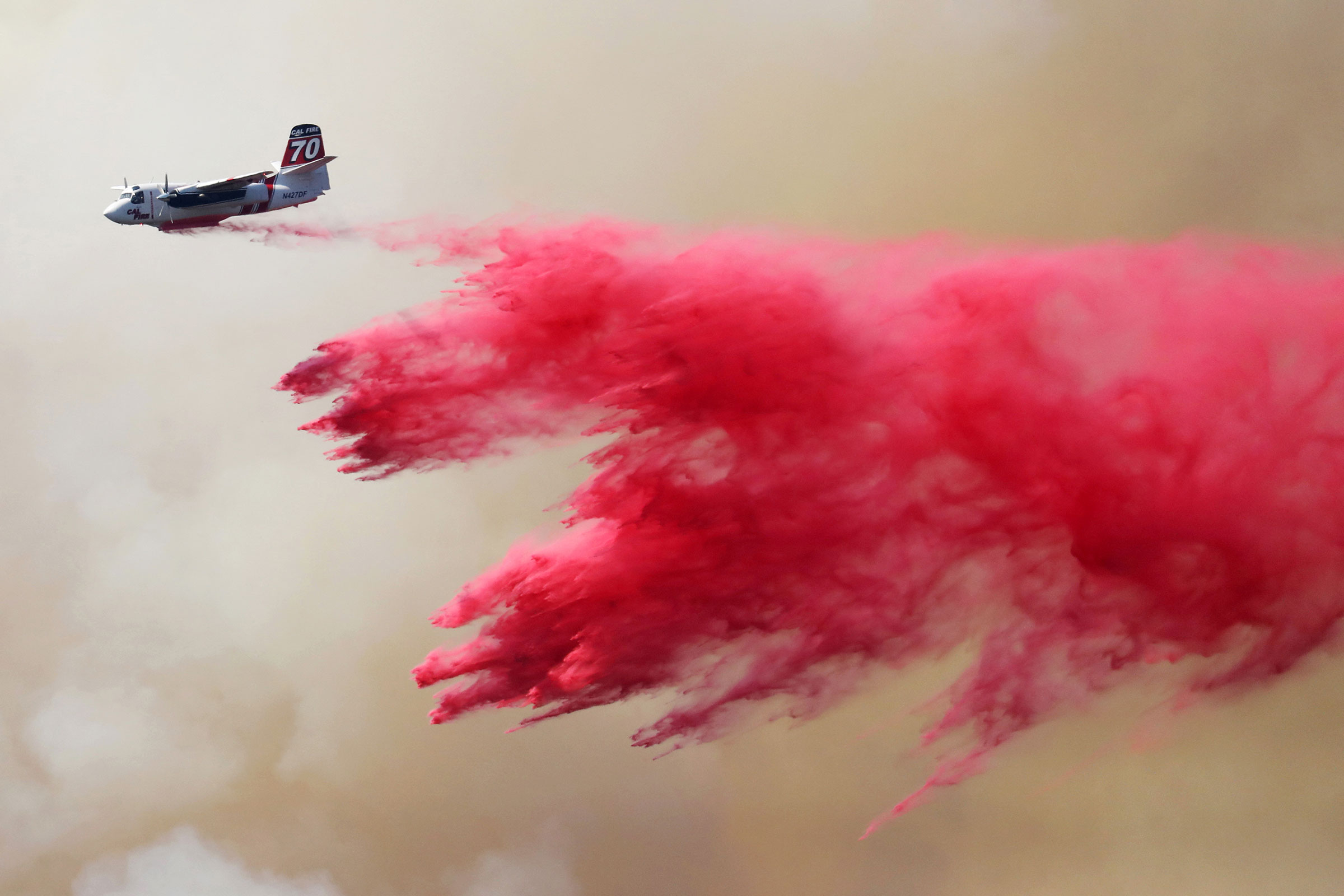 A CAL FIRE aircraft drops Phos-Chek on the Oak Fire near Darrah in Mariposa County, Calif., on July 24, 2022. (David Swanson—Reuters)
