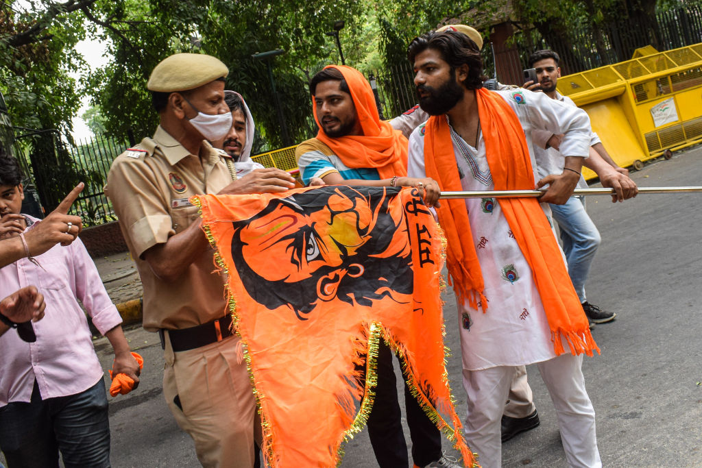 Security personnel tries to take the flag from a member of a right-wing Hindu group during a June 29 protest in New Delhi against the killing of Kanhaiya Lal, a tailor from Udaipur who was killed by two Muslim men. (Kabir Jhangiani—Pacific Press/LightRocket/Getty Images)