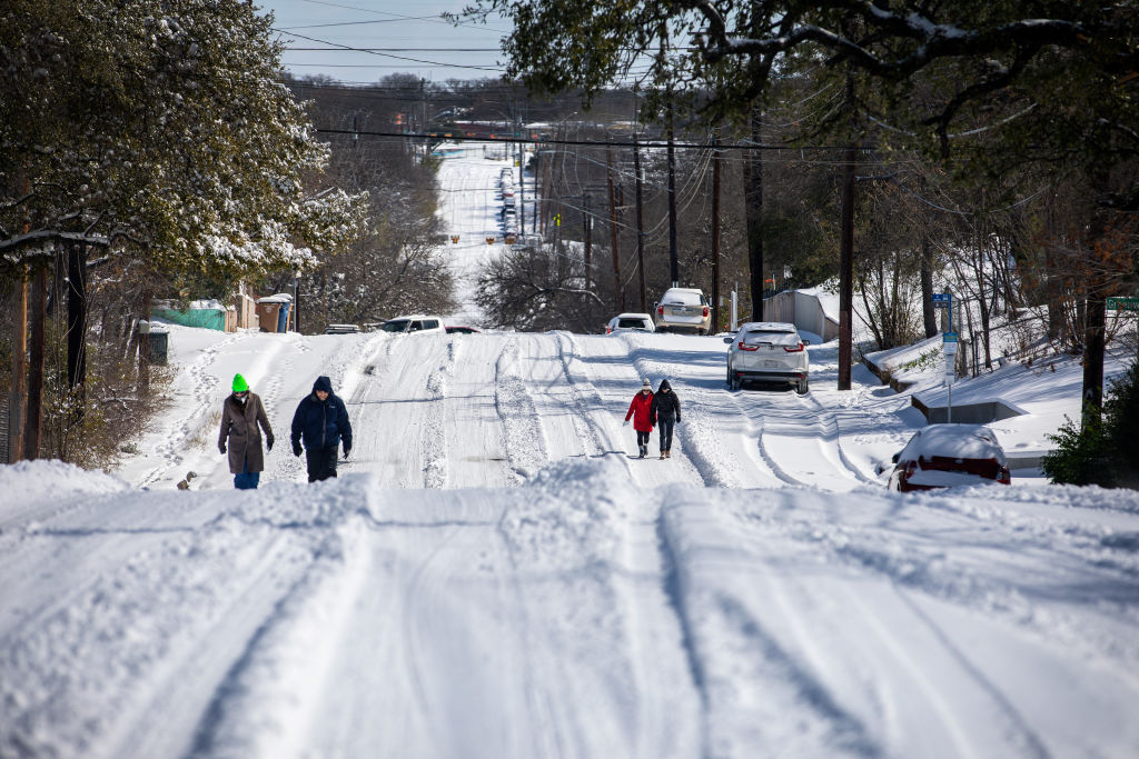 Pedestrians walk on an icy road in East Austin, Texas, on February 15, 2021 (Montinique Monroe— Getty Images)