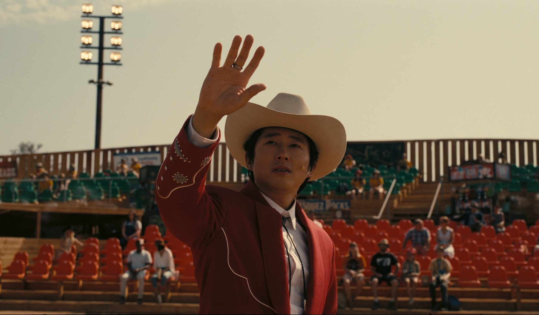 Steven Yeun as Ricky gestures up toward the sky