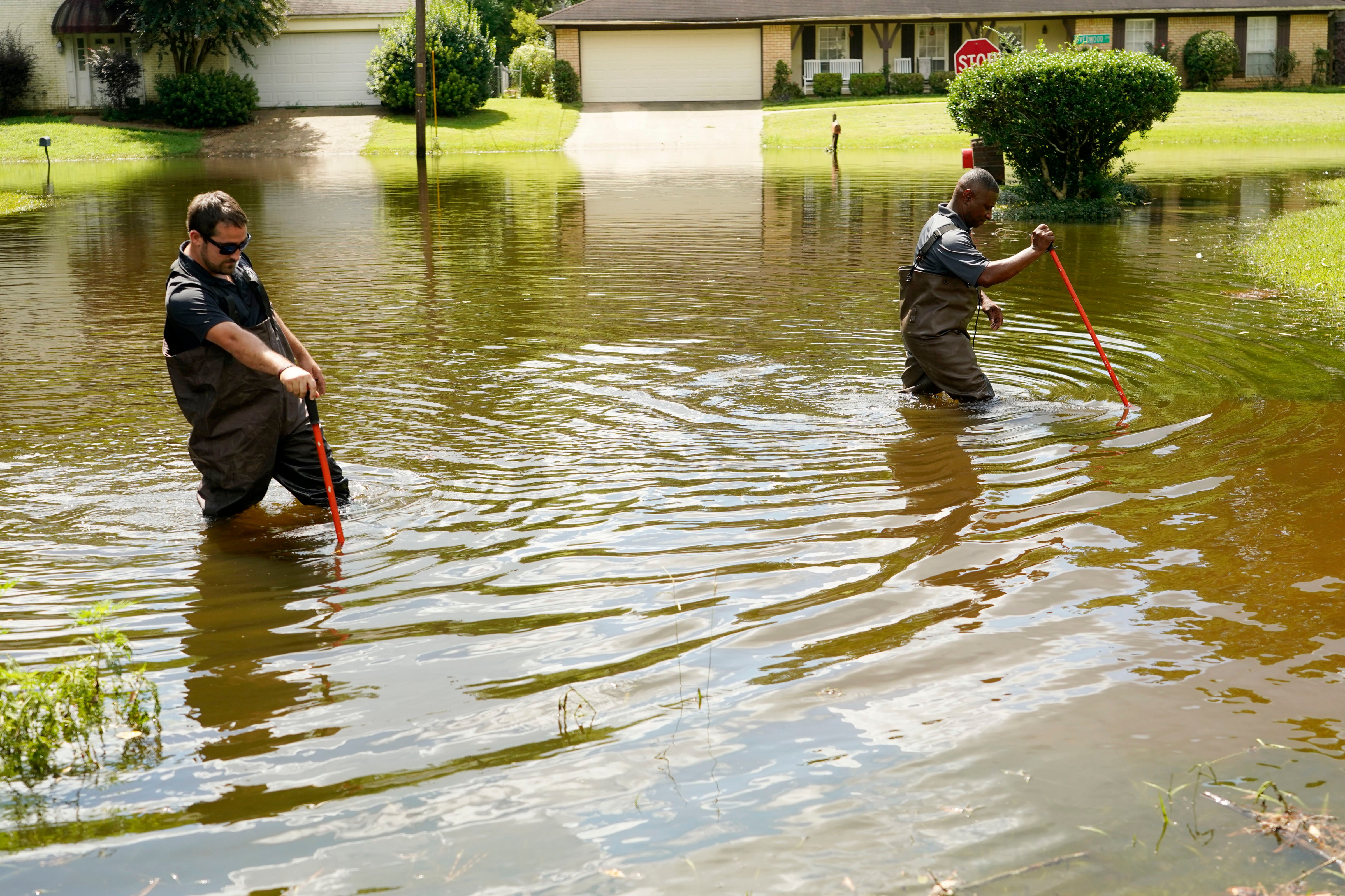 Hinds County Emergency Management Operations deputy director Tracy Funches, right, and operations coordinator Luke Chennault, wade through flood waters in northeast Jackson, Miss., Monday, Aug. 29, 2022, as they check water levels. Flooding affected a number neighborhoods that are near the Pearl River. (Rogelio V. Solis–AP)