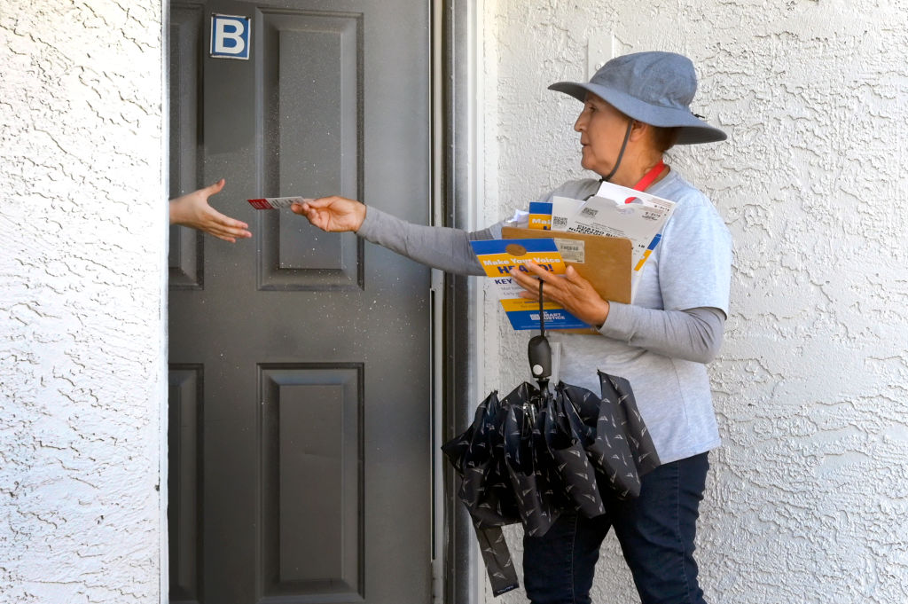 Culinary Union member Maria Orozco hands voter information to a resident as she canvasses at an apartment complex in Las Vegas, Nevada on June 8, 2022, ahead of the state's primaries. (David Becker—Washington Post via Getty Images)