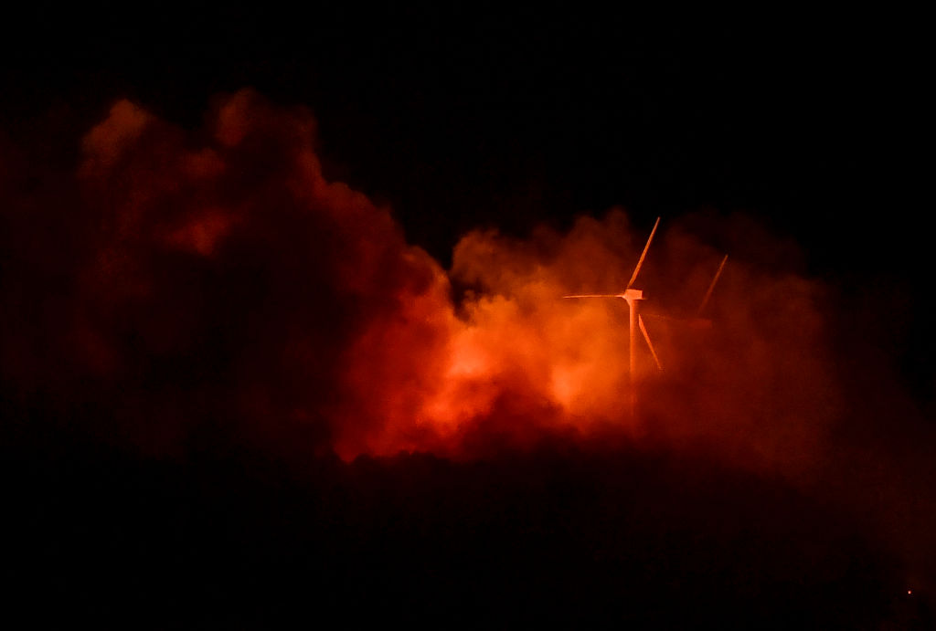 The blaze of a wildfire lights up wind turbines on top of a mountain in  the Moncayo Natural Park in the northern region of Aragon, seen from the town of Borja, late on August 14, 2022. - Hundreds of firefighters battled a blaze in northern Spain today that forced hundreds to evacuate and devastated swathes of land, officials said. (ANDER GILLENEA-AFP/Getty Images)
