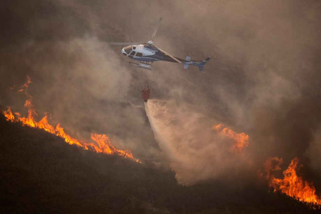 A firefighter helicopter drops water to put out a wildfire in the Baixa Limia - Serra do Xures Natural Park near the village of Lobeira, Ourense province, northwestern Spain, on August 25, 2022. (MIGUEL RIOPA- AFP/Getty Images))