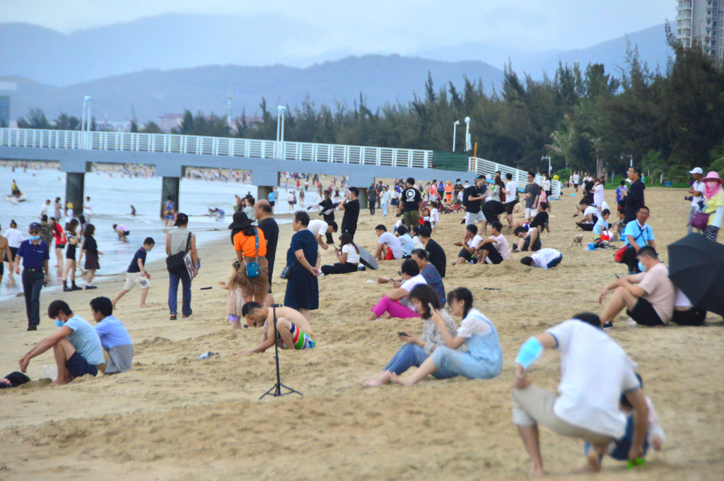 Tourists sit on the beach at Sanya Bay during the May Day holiday on May 1, 2022 in Sanya, Hainan, China. (Sun Qing/VCG via Getty Images)