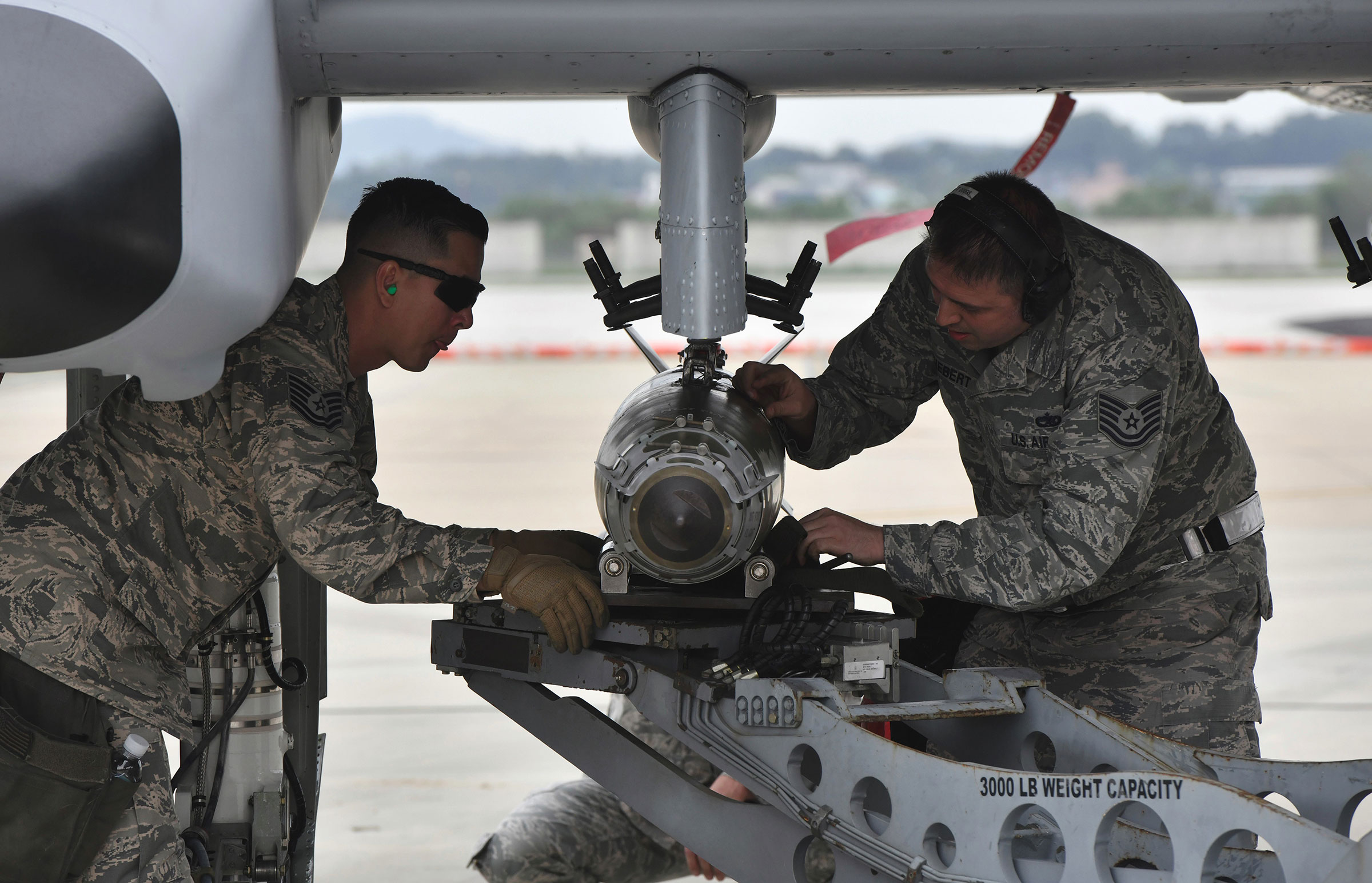 U.S. airmen inspect a bomb loaded onto an A-10 Thunderbolt II close air support aircraft during a demonstration during 