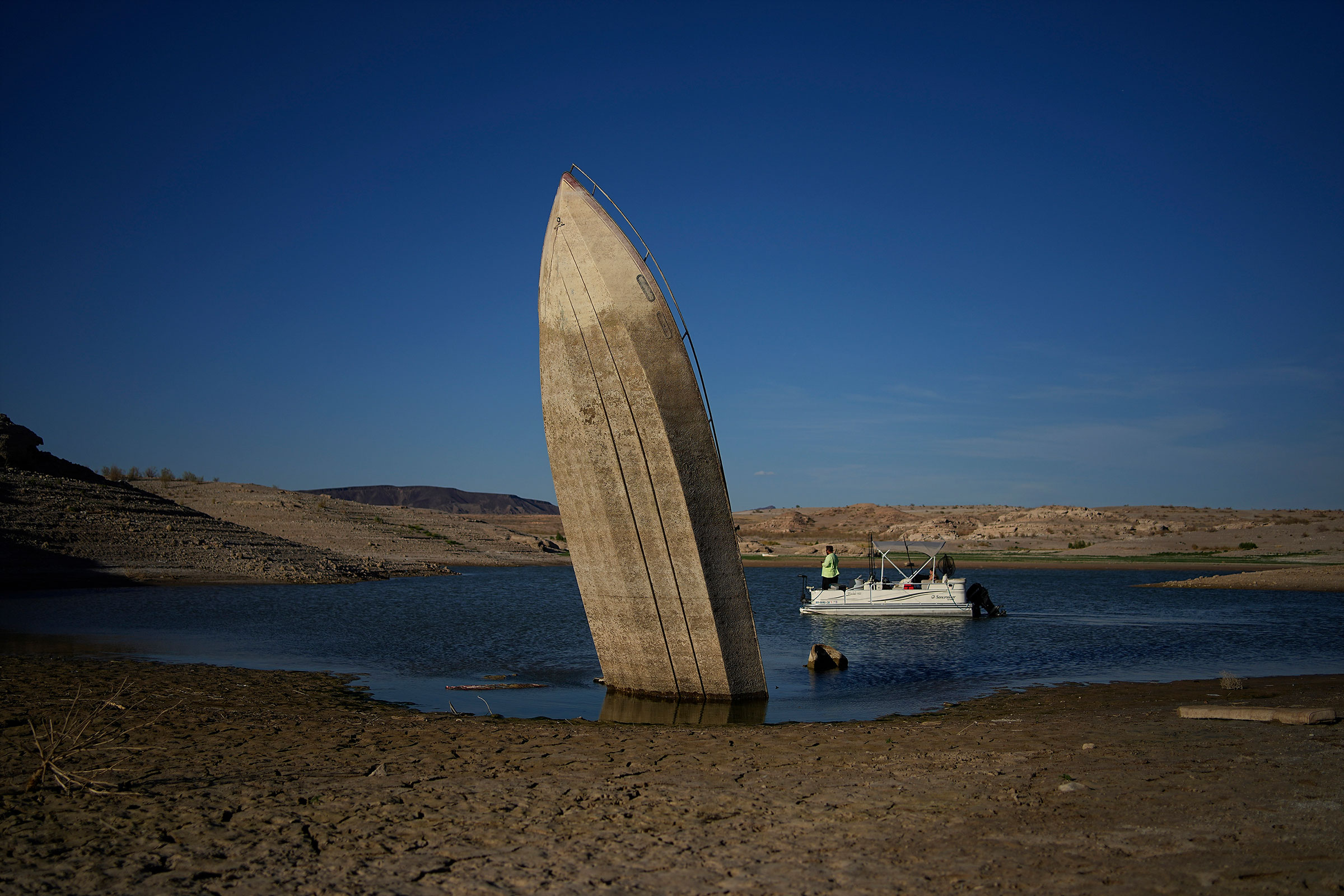 A formerly sunken boat sits upright into the air with its stern stuck in the mud along the shoreline of Lake Mead at the Lake Mead National Recreation Area, near Boulder City, Nev. on June 10, 2022. (John Locher—AP)