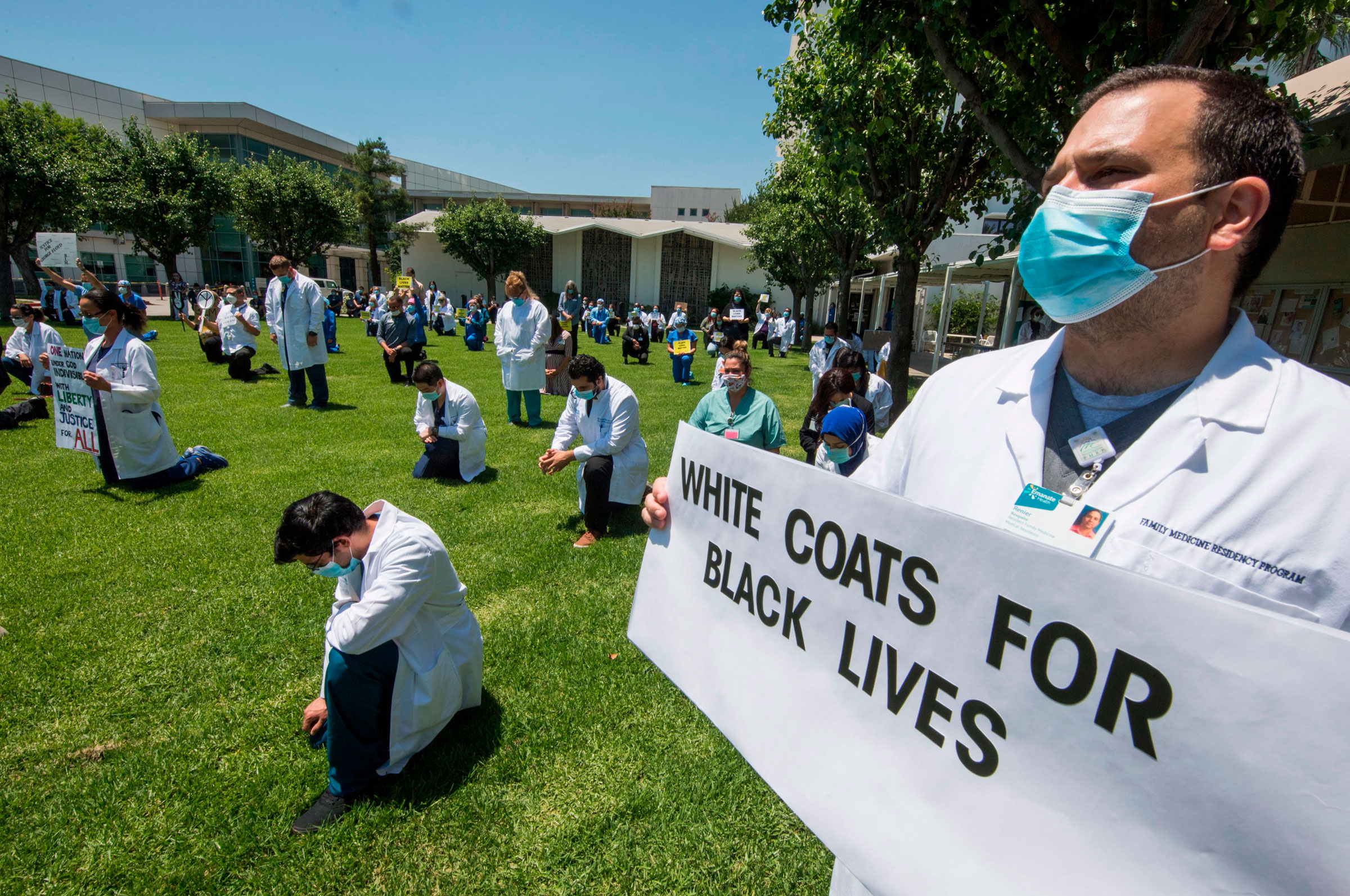 People kneel as doctors, nurses and other health care workers participate in a 