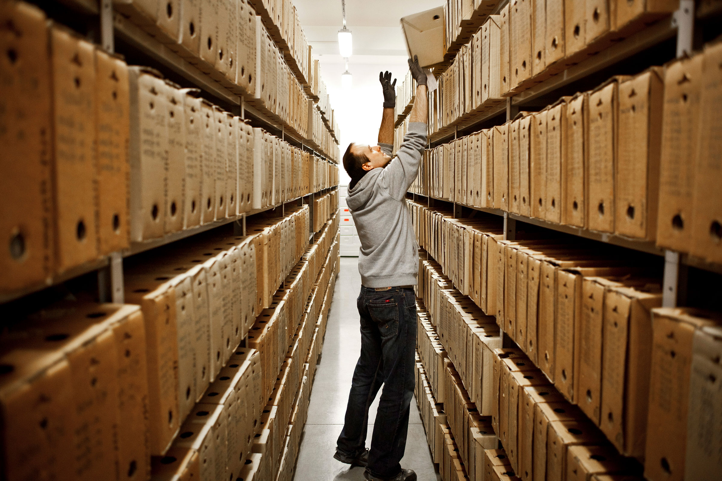 A man sorting through files stored on shelves at the​ Instytut Pamieci Narodowej (I​PN), the Institute for Nationa​l Rememberance, in Warsaw