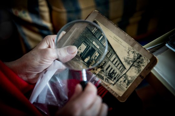 A Holocaust survivor, looks at photos of property her family owned in Poland before the war