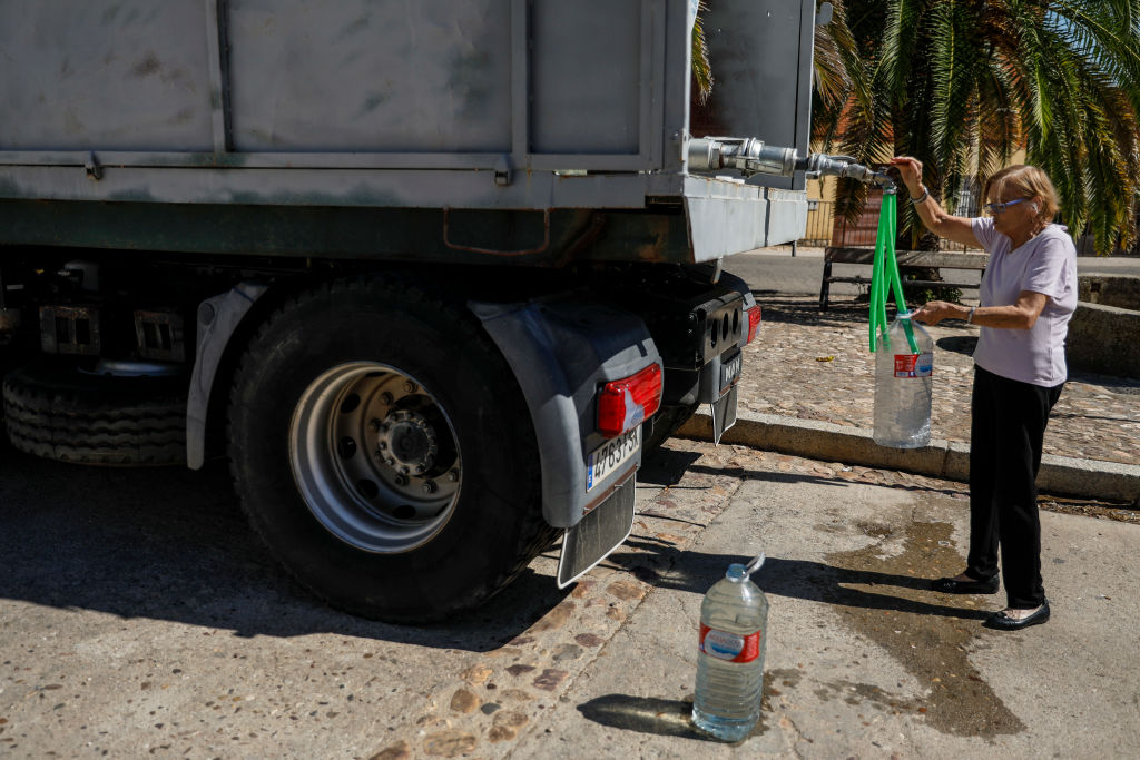 People collect drinking water from a tanker truck due to low water levels and contamination of the nearby reservoir on July 28, 2022 in Peraleda de San Roman, Caceres province, Spain. (Pablo Blazquez Dominguez—Getty Images)