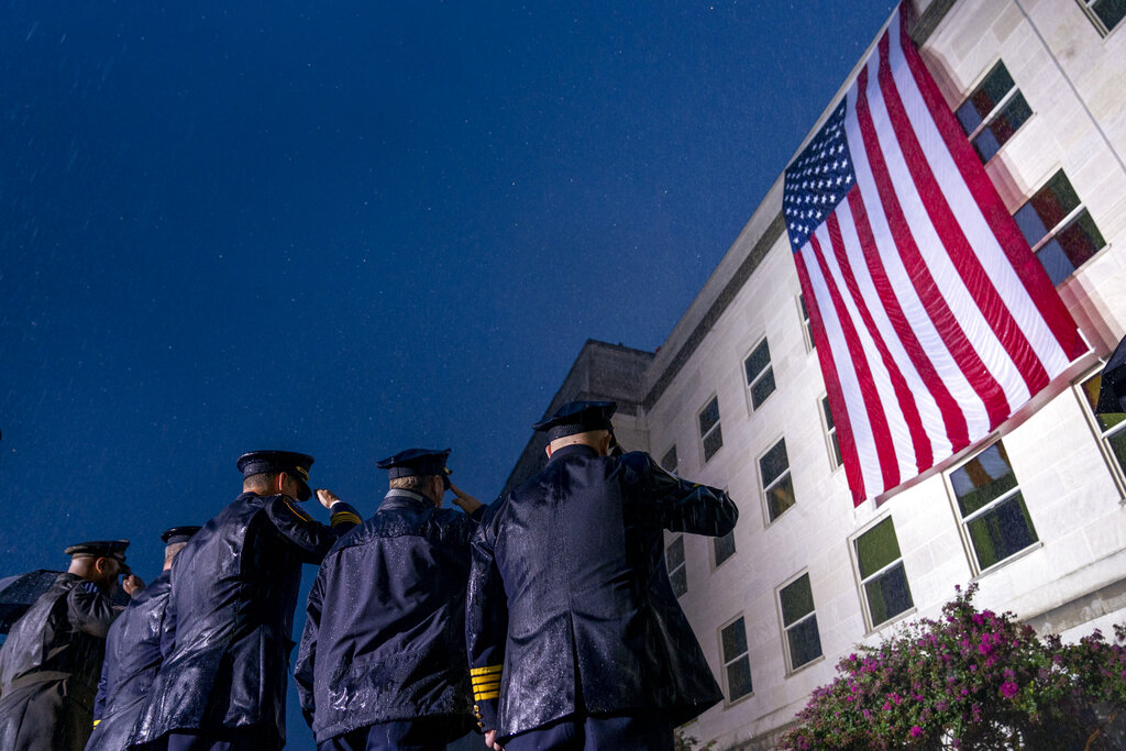 First responders salute in a driving rain as a U.S. flag is unfurled at the Pentagon in Washington, on Sept. 11, 2022. (Andrew Harnik—AP)