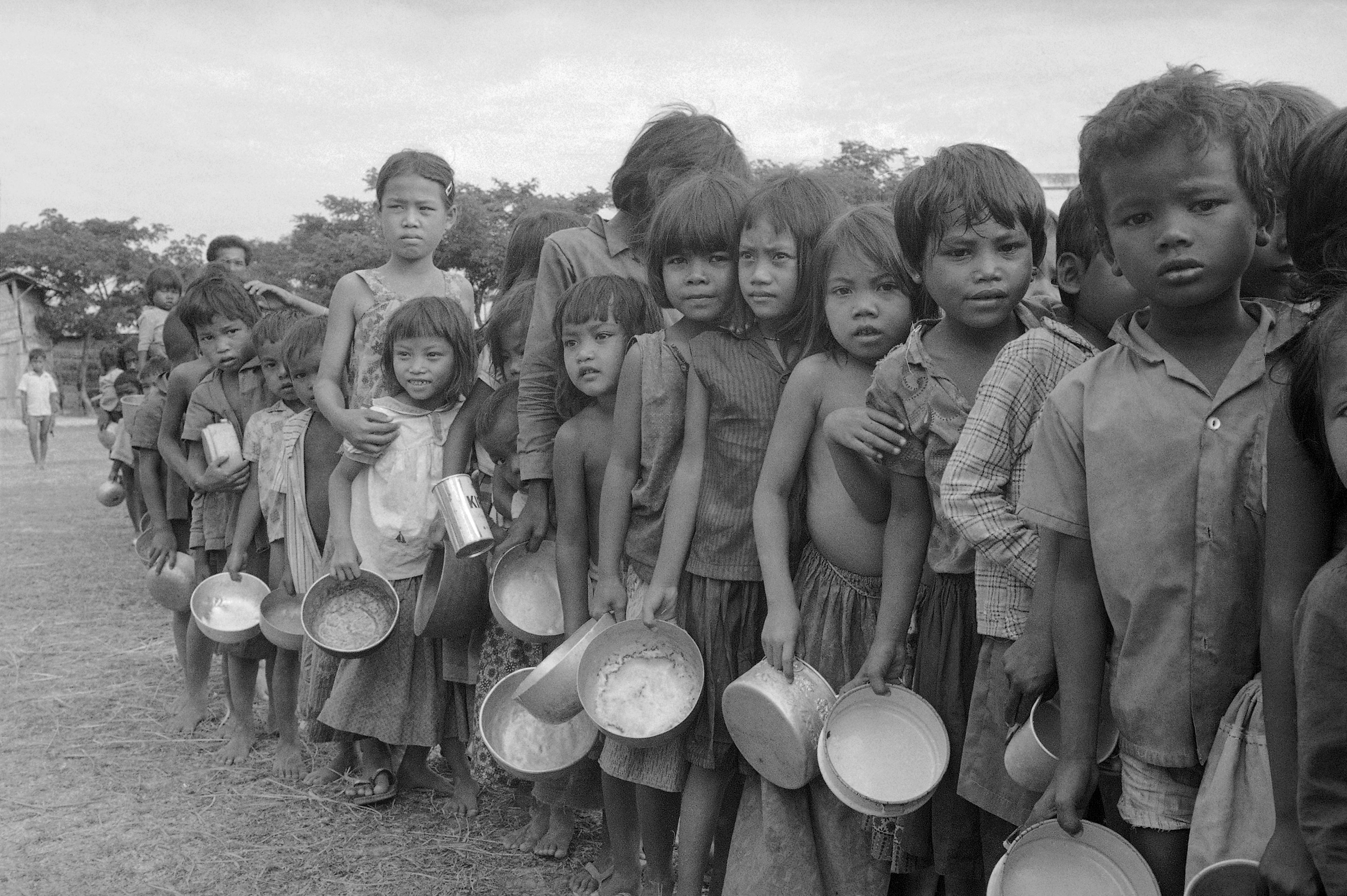 Cambodian refugee children wait their turn at an aid organization's feeding station northwest of Phnom Penh, Cambodia, January 9, 1975. The youths and their families fled the Phnom Basset area after Khmer Rouge raids nearby.  (Tea Kim Heang aka Moonface—AP)