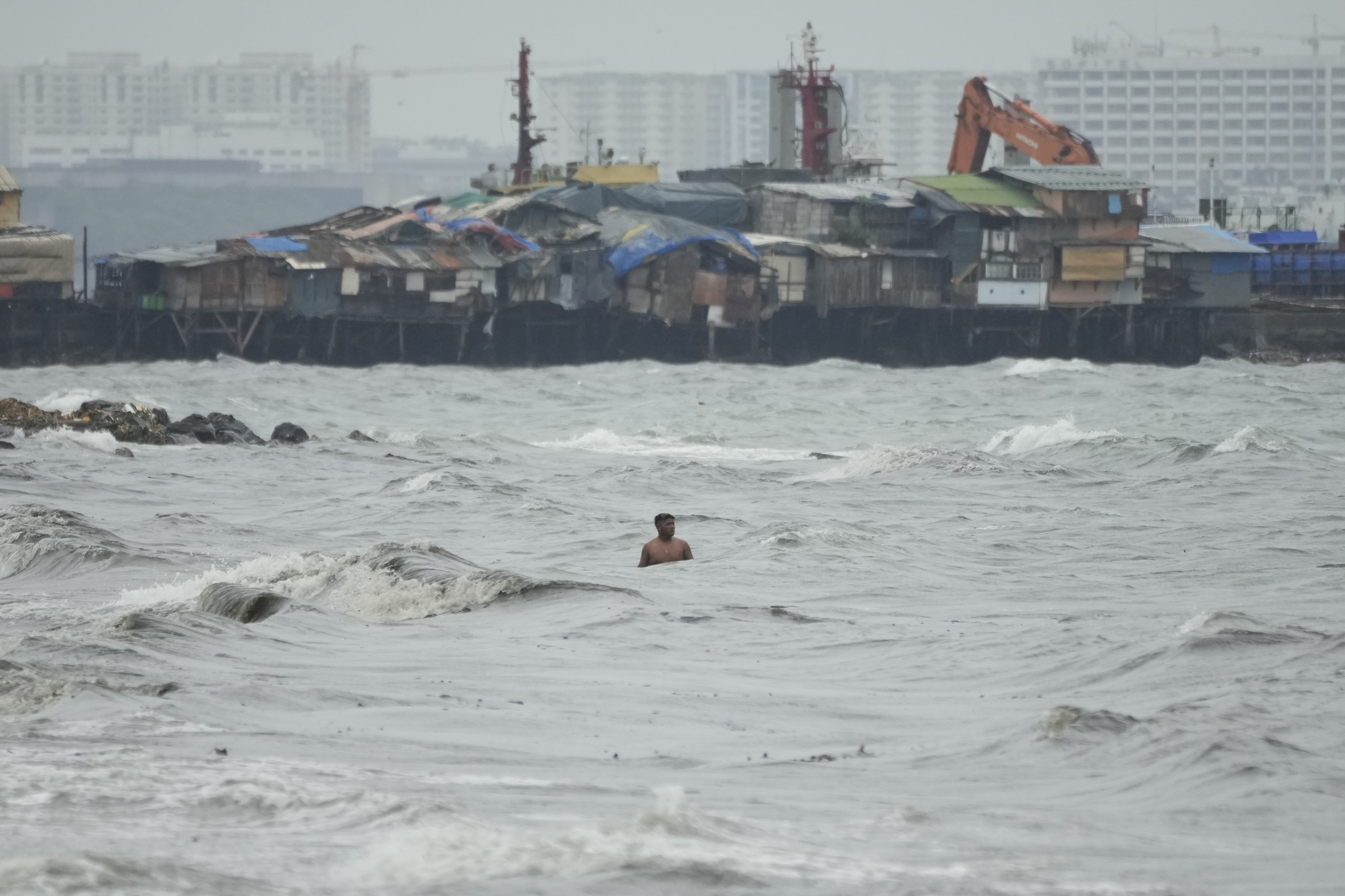 A resident swims past strong waves as Typhoon Noru approaches the coastal district of Tondo in Manila, Philippines, Sunday, Sept. 25, 2022. (Aaron Favila—AP)