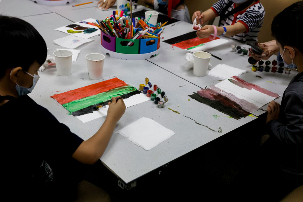 Young Afghan children paint a piece of paper with the colors of the national flag of Afghanistan in an art class at the National Conference Center in Leesburg, Virginia.