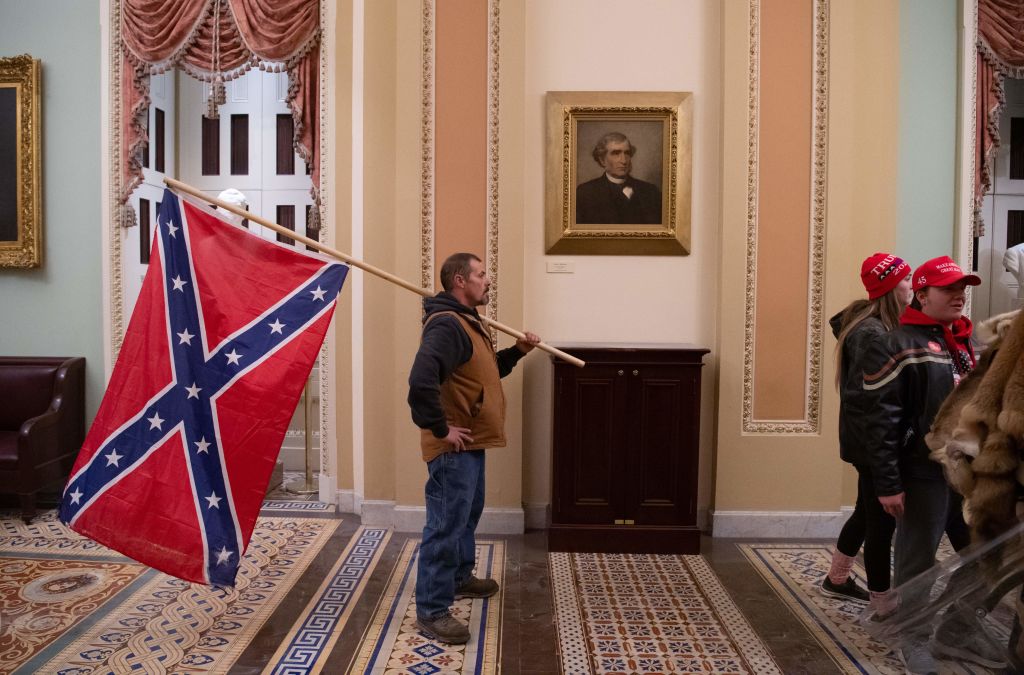 A supporter of US President Donald Trump holds a Confederate flag outside the Senate Chamber during a protest after breaching the US Capitol in Washington, DC, January 6, 2021. - The demonstrators breeched security and entered the Capitol as Congress debated the 2020 presidential election Electoral Vote Certification. (SAUL LOEB-AFP)