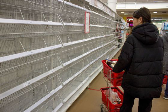 A woman looks at empty shelves in a supermarket in Moscow.