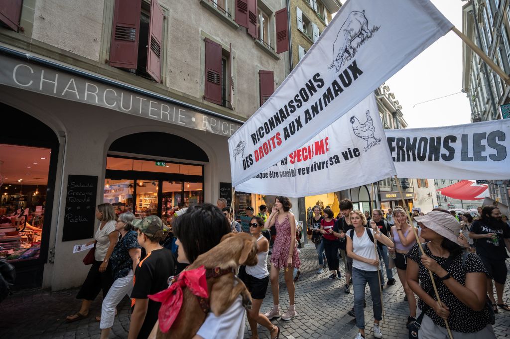 Activists hold a banner reading in French "let's recognize some rights for animals" as they walk past a delicatessen during a protest in Lausanne, western Switzerland on Aug. 27, 2022. (Fabrice Coffrini—AFP/Getty Images)