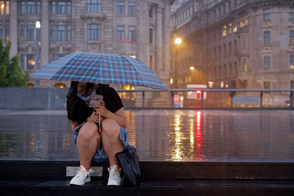 A tourist sits in the rain on Sept. 4, 2022 in Shanghai, China as Typhoon Hinnamnor approaches. (Yin Liqin/China News Service via Getty Images)