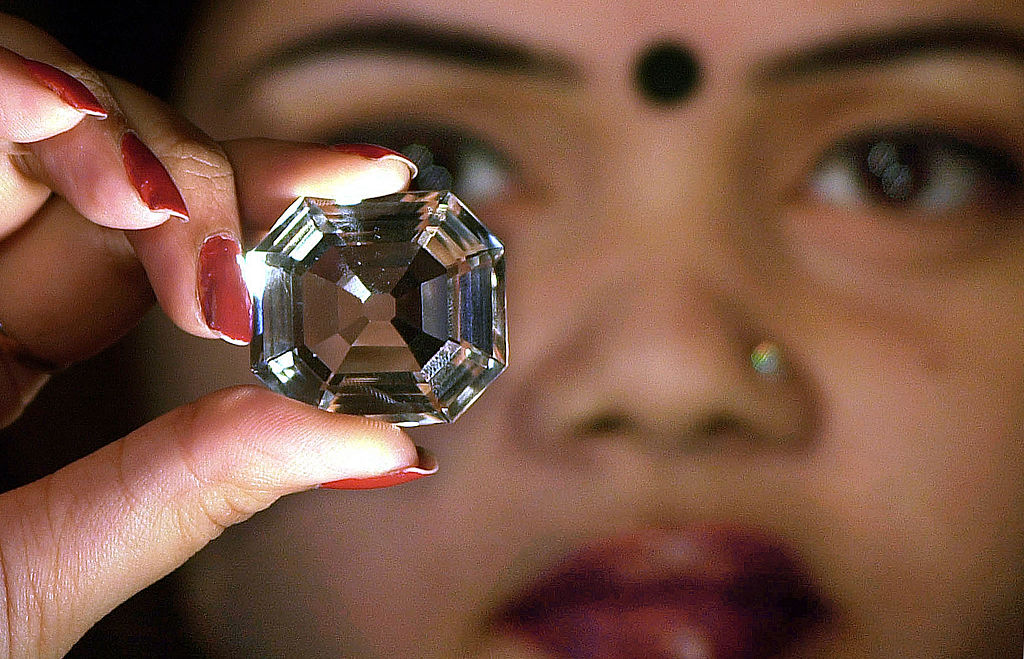 An Indian model shows a replica of the famous Indian diamond Kohinoor during a press meeting in Calcutta, 29 January 2002. (DESHAKALYAN CHOWDHURY/AFP via Getty Images)