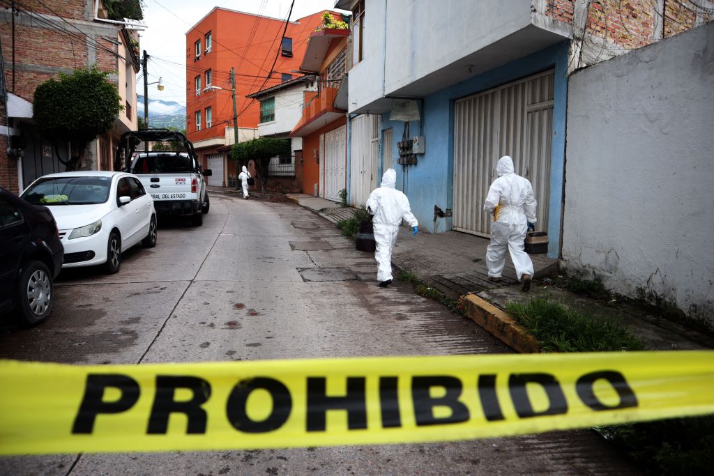Police investigators in forensic suits inspect the area around the vehicle in which journalist Fredid Román was shot dead, in front of the newspaper La Realidad in Chilpancingo, state of Guerrero, Mexico, on August 22, 2022. (Jesus Guerrero—AFP/Getty Images)