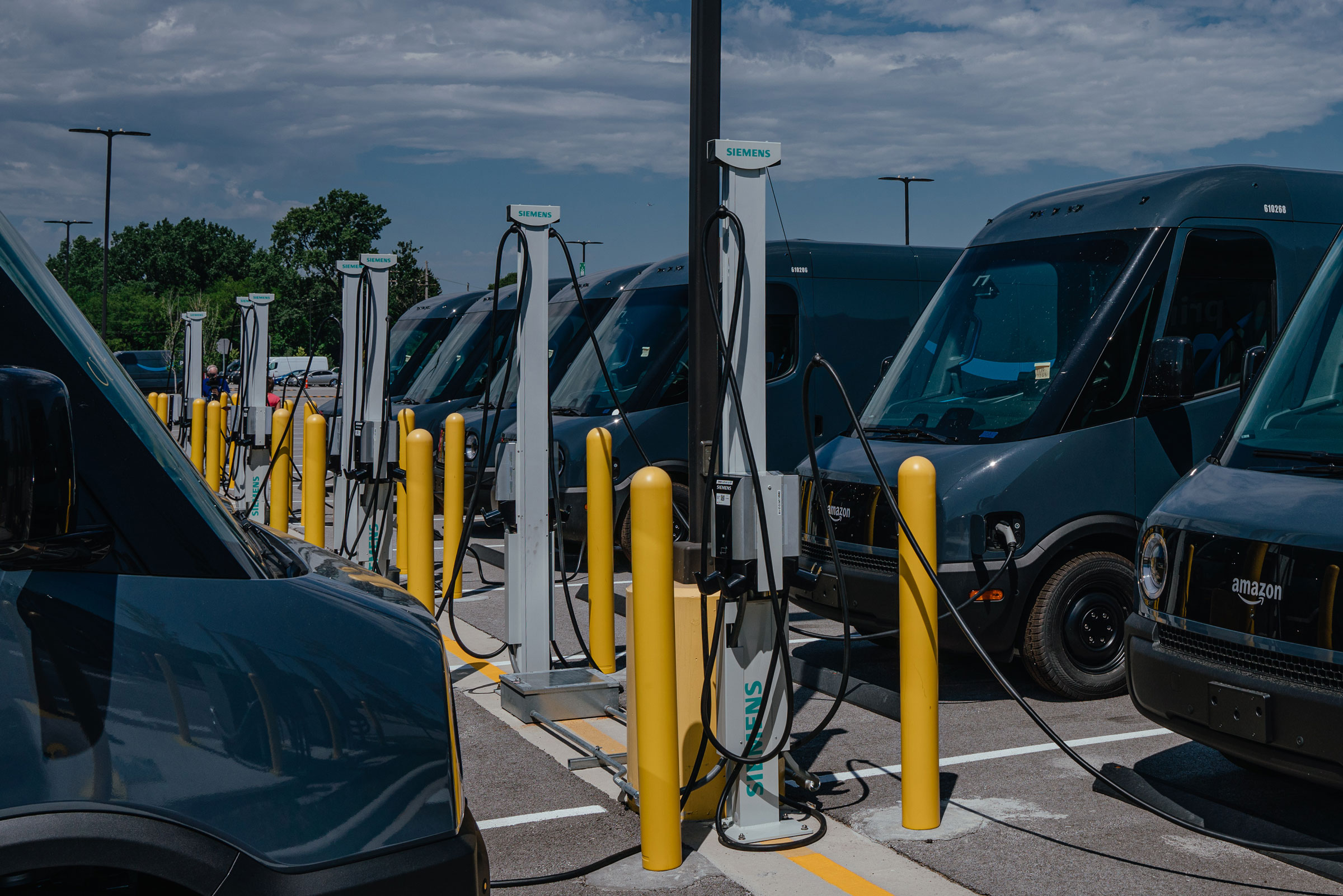 Amazon delivery electric vans plugged into electric charging stations