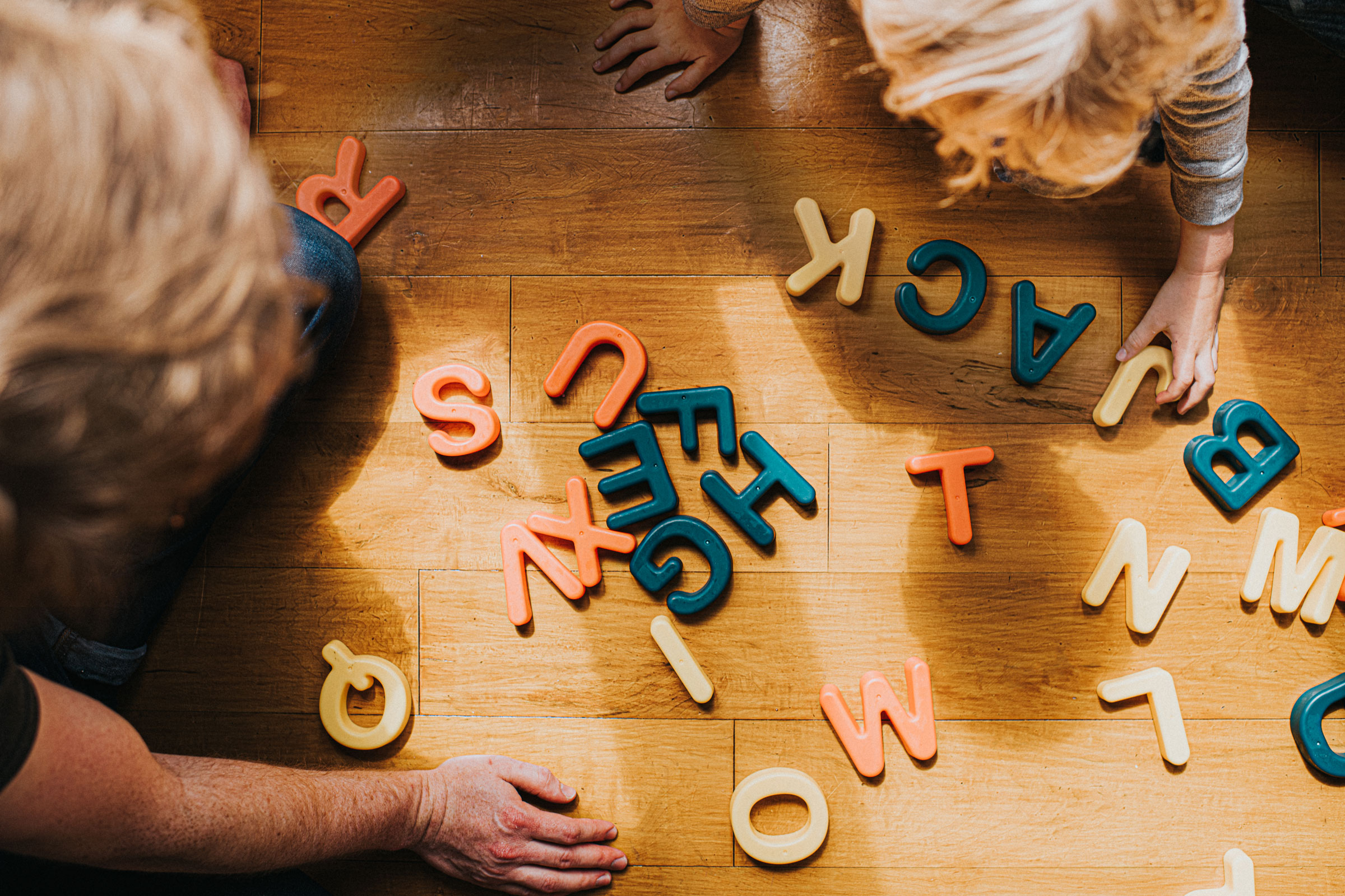 Child arranges colourful capital letters to create words