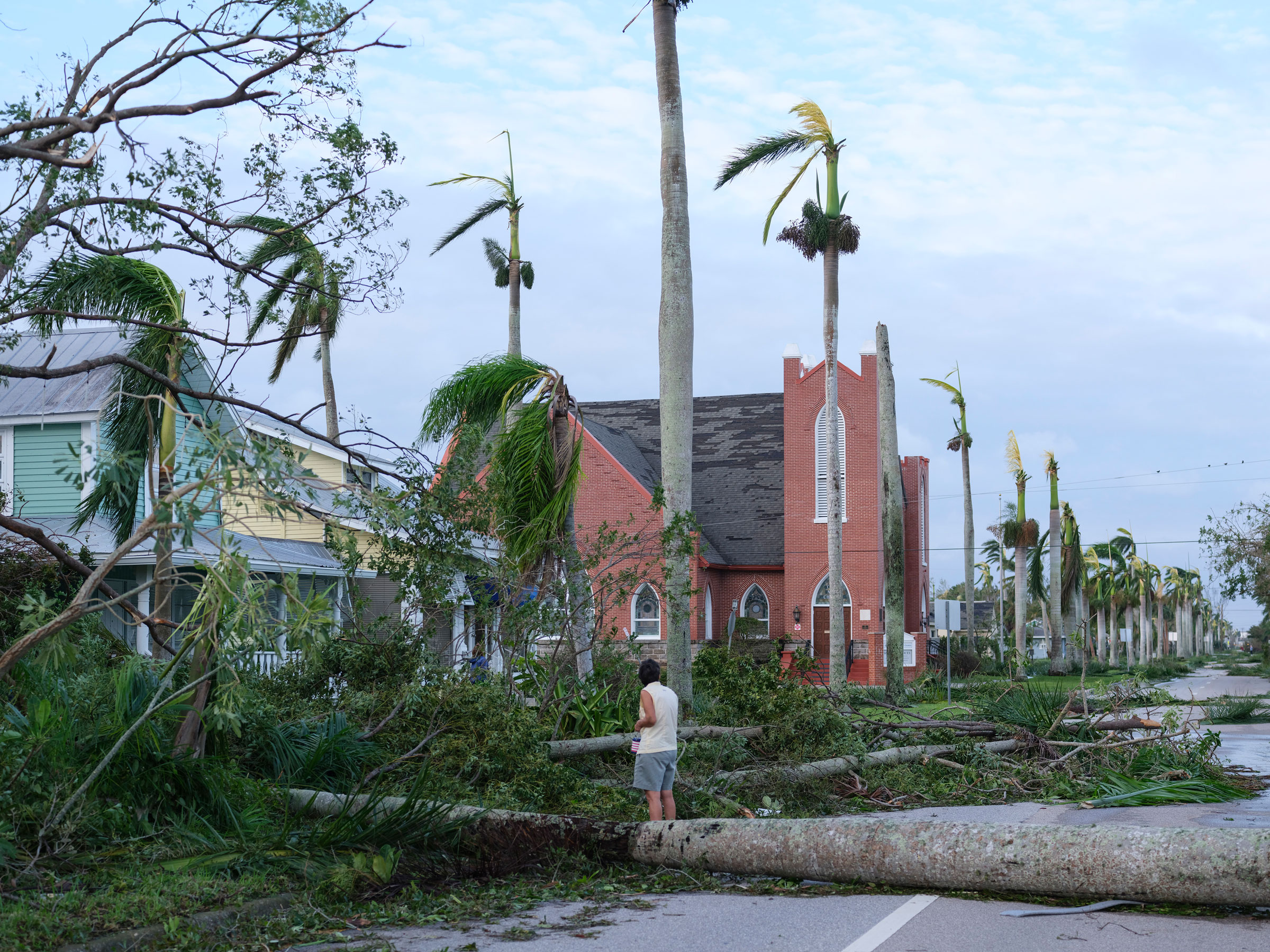 Residents emerge at dawn on Sept. 29, 2022, in downtown Crow Gables, Fla., where trees along the street were toppled by Hurricane Ian. (Christopher Morris for TIME)