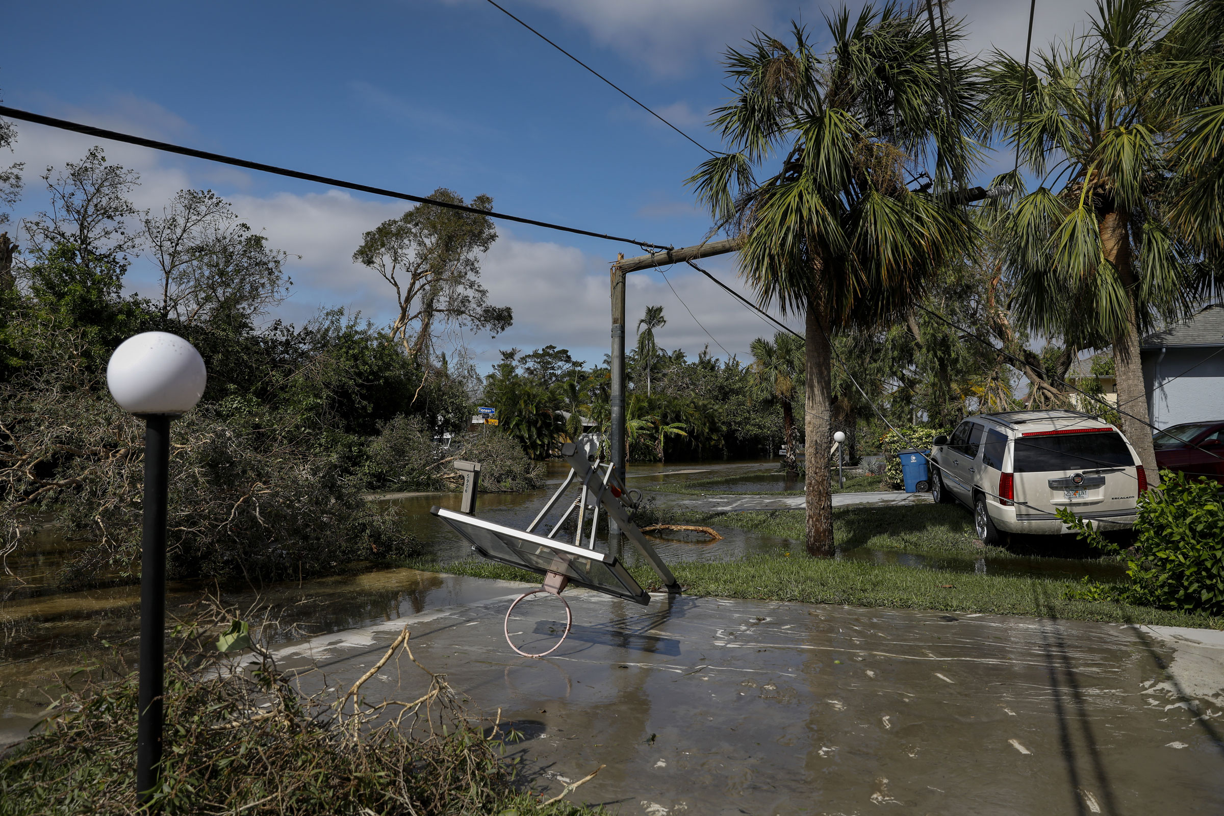 A broken utility pole behind a collapsed basketball hoop on a flooded street following Hurricane Ian in Fort Myers, Fla., on Sept. 29. (Eva Marie Uzcategui—Bloomberg/Getty Images)