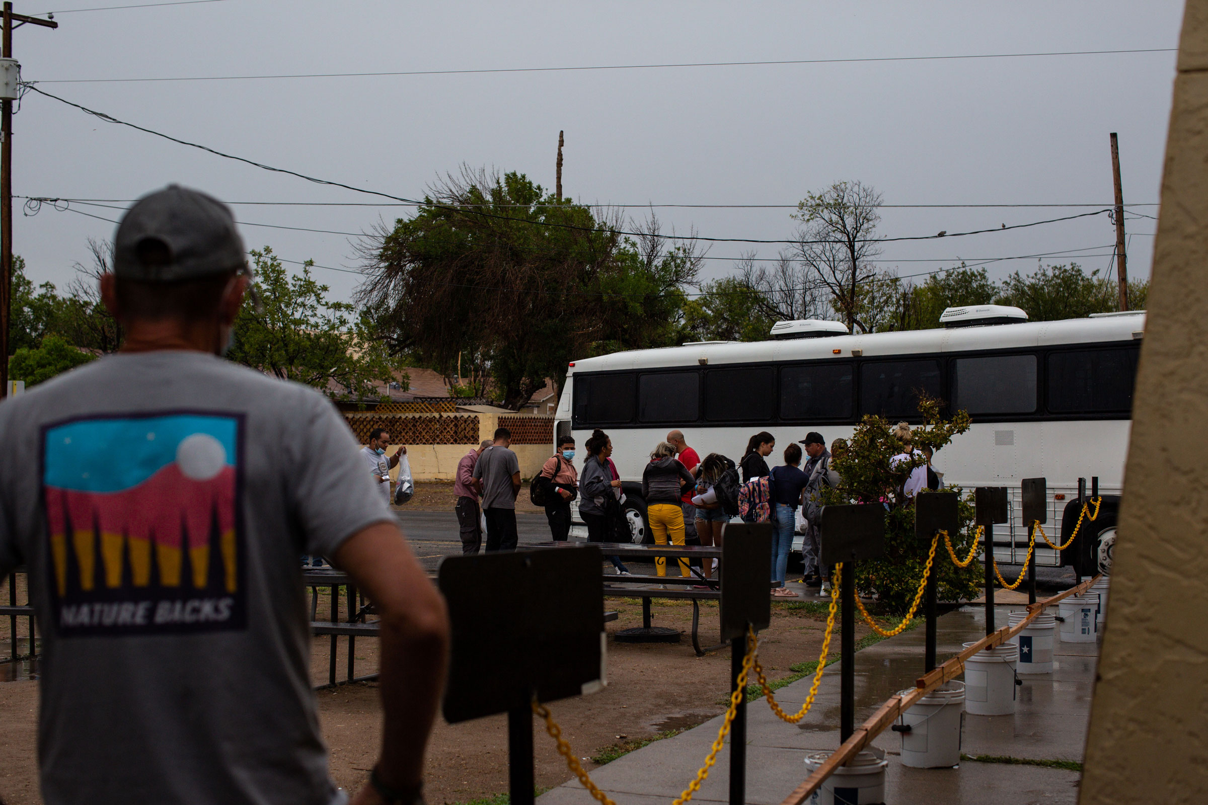 A Val Verde Border Humanitarian Coalition volunteer prepares to receive the first bus of migrants arriving for travel assistance in Del Rio
