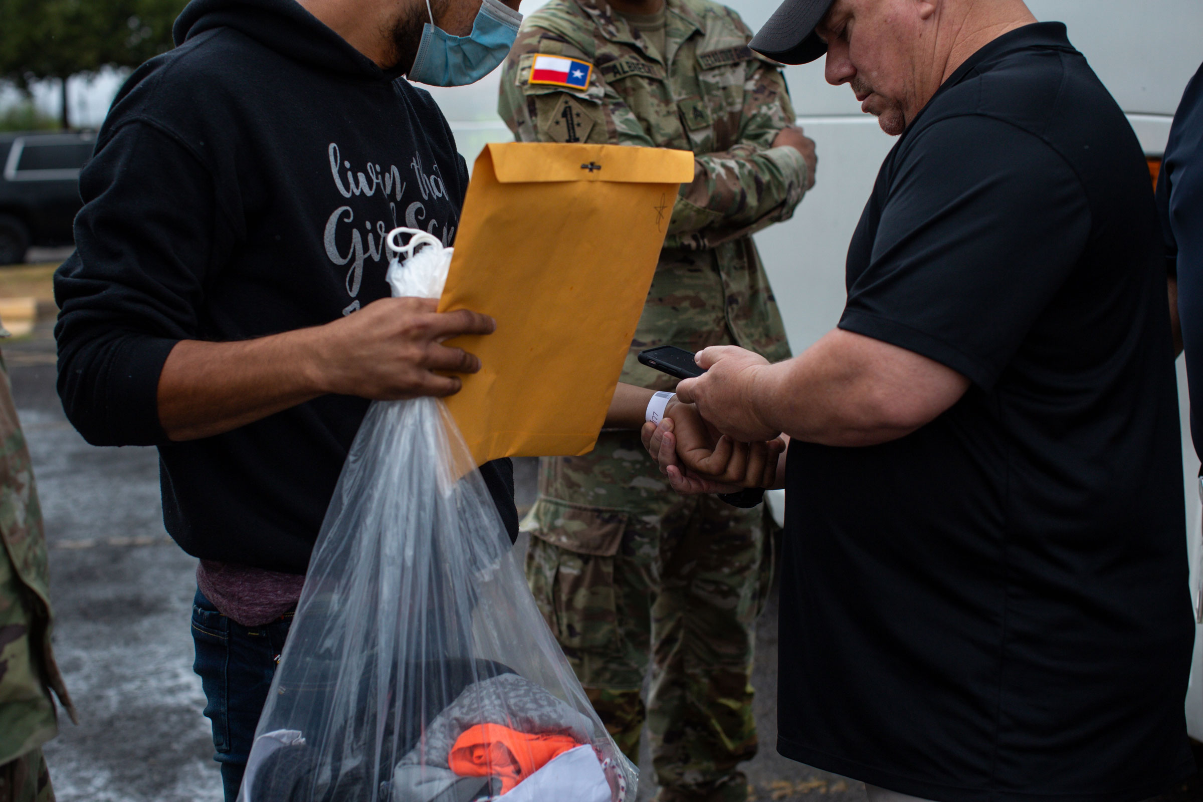 An official scans Jhason's assigned barcoded wristband required to travel on an Operation Lone Star bus to either Washington, D.C. or New York, New York, from the Val Verde Border Humanitarian Coalition in Del Rio, Texas, on Aug. 15, 2022. (Kaylee Greenlee Beal for TIME)