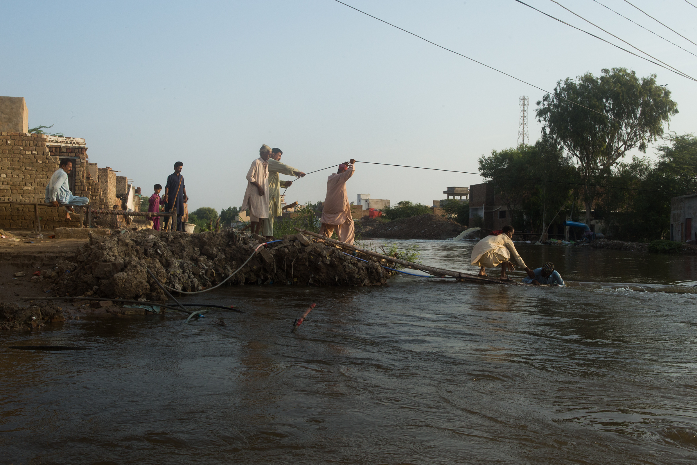 Residents rush to save a man from drowning on an embankment between Hayat Haskheli village and Judo town, September 9.  (Hasan Gondal for TIME)