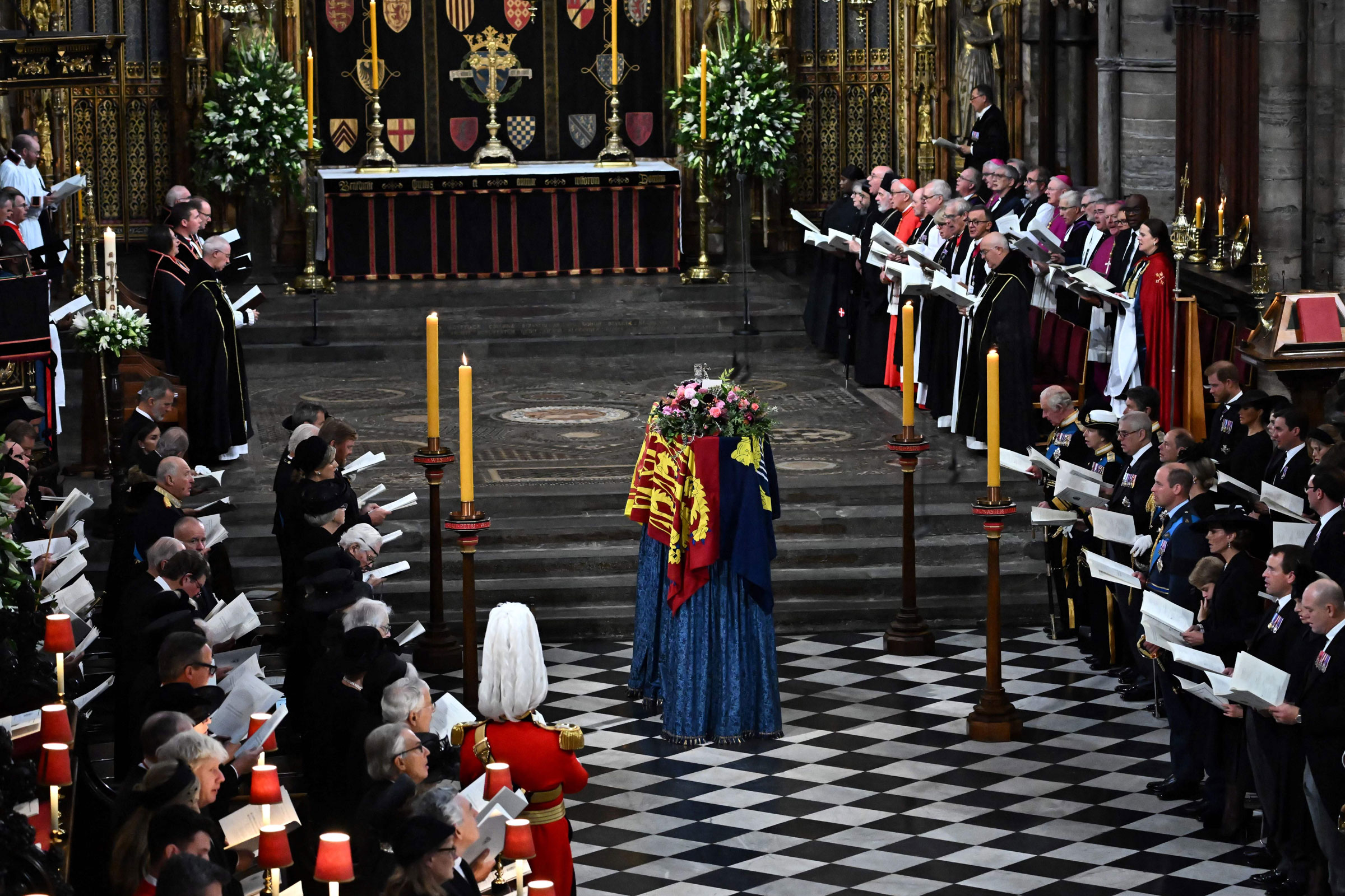 Members of the Royal family and guests sing as the coffin of Queen Elizabeth II, draped in the Royal Standard, lies by the altar during the State Funeral Service for Britain's Queen Elizabeth II at Westminster Abbey in London.