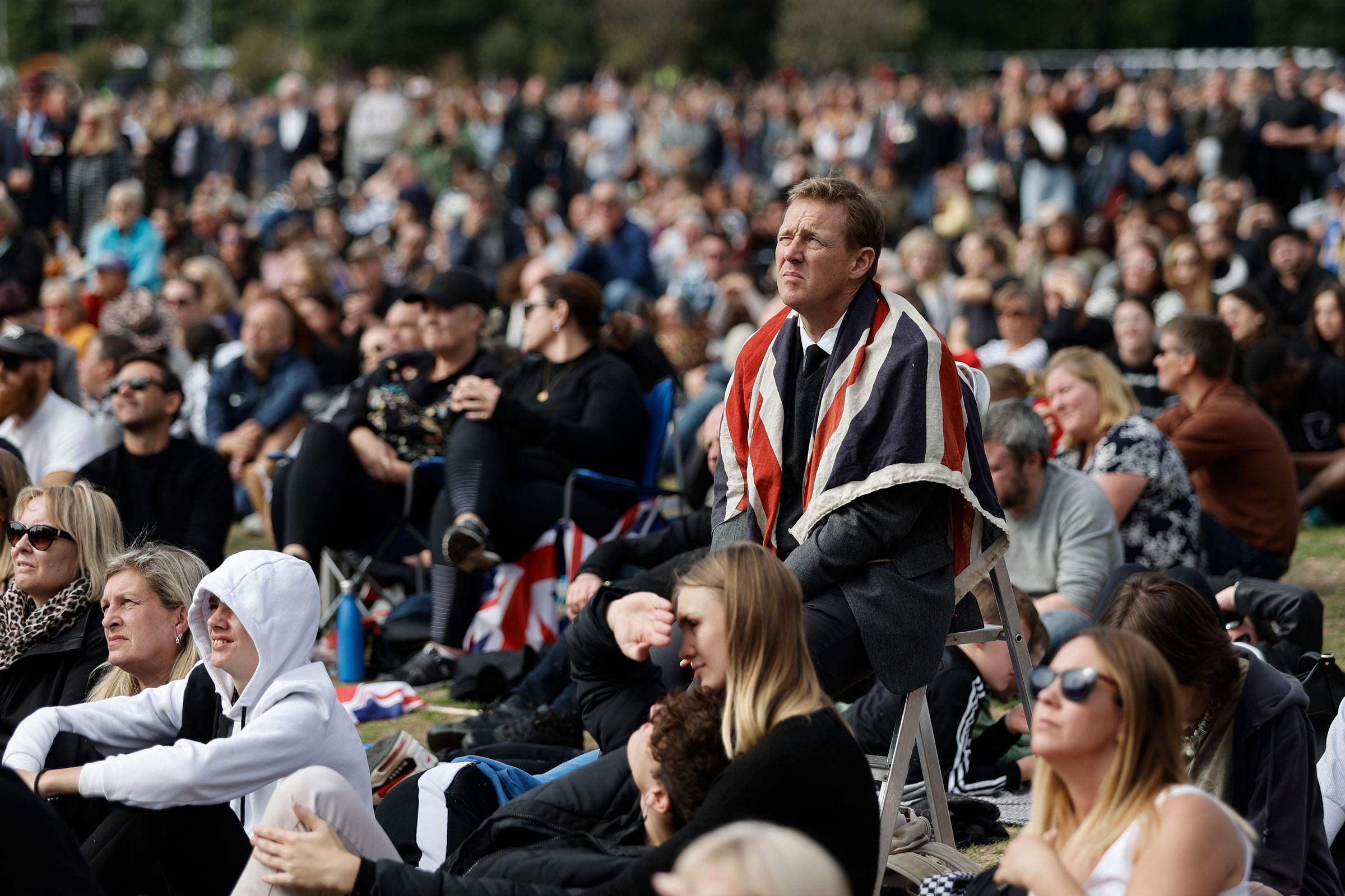 People in Hyde Park, in London, watch the State Funeral Service of Britain's Queen Elizabeth II on giant screens.