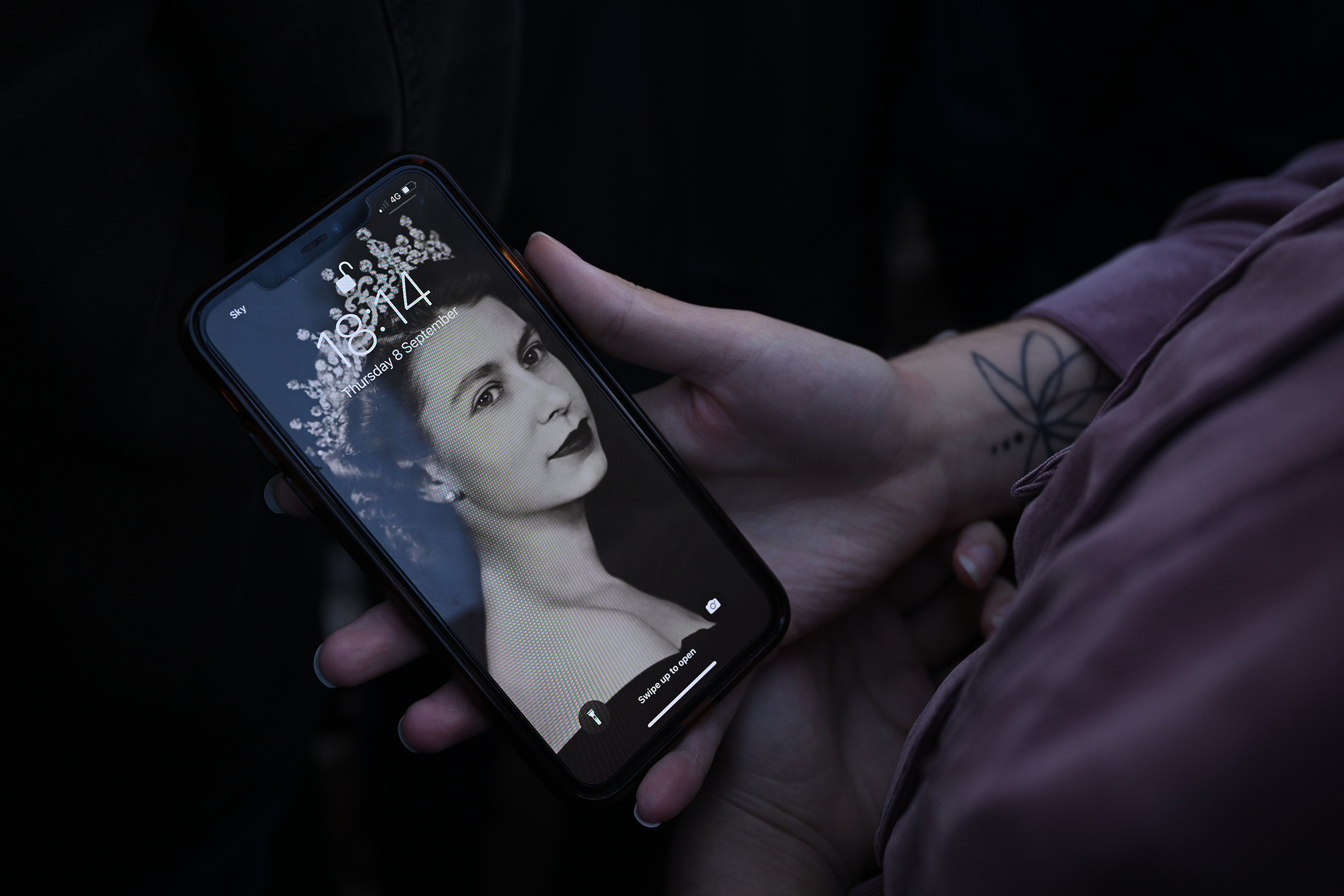 Una persona sostiene su teléfono con un protector de pantalla de la reina Isabel II el 8 de septiembre de 2022 en Londres.  (León Neal—Getty Images)