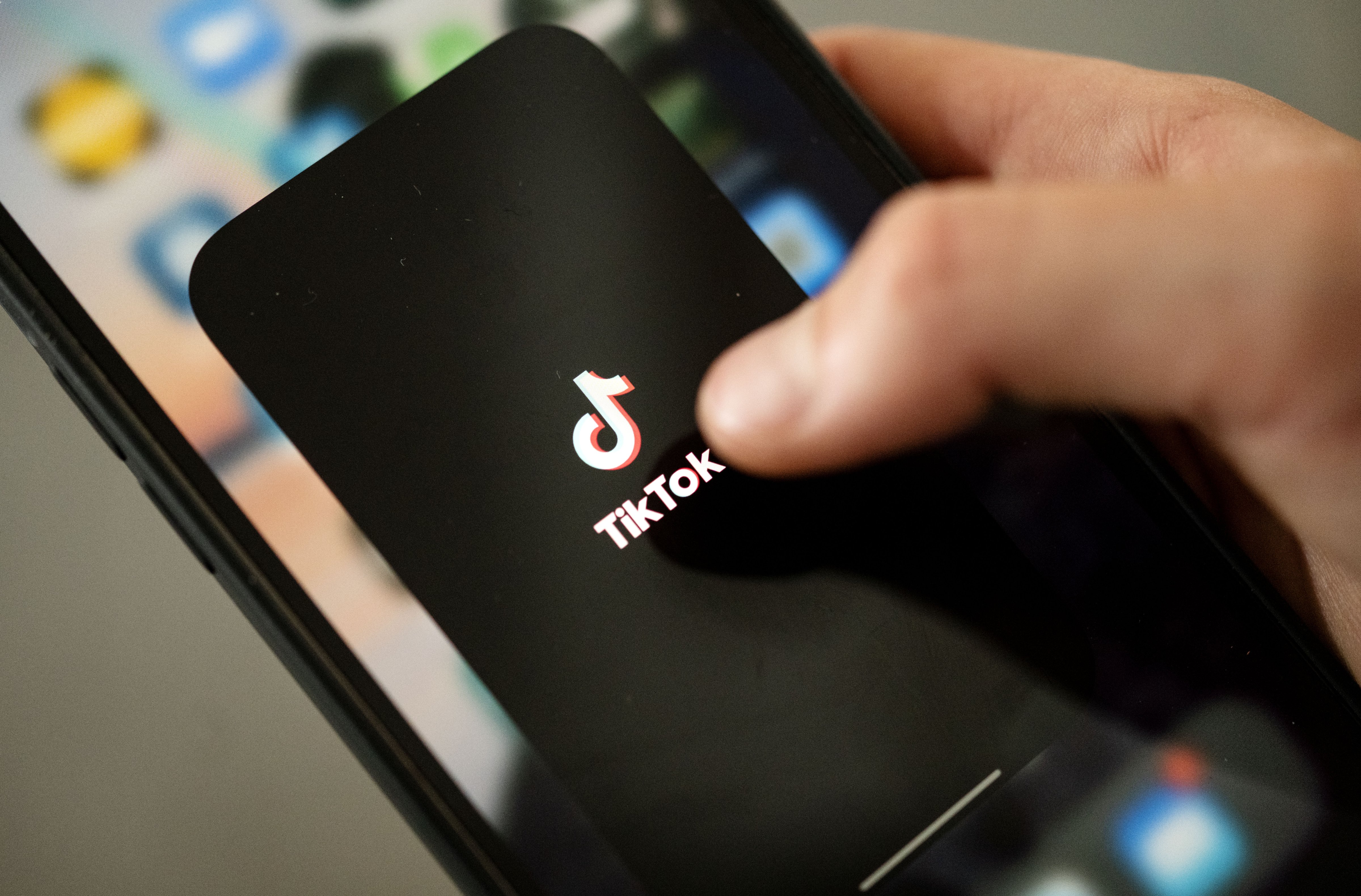 A teenager taps the TikTok logo on a smartphone. (Marijan Murat - picture alliance / Getty Images)