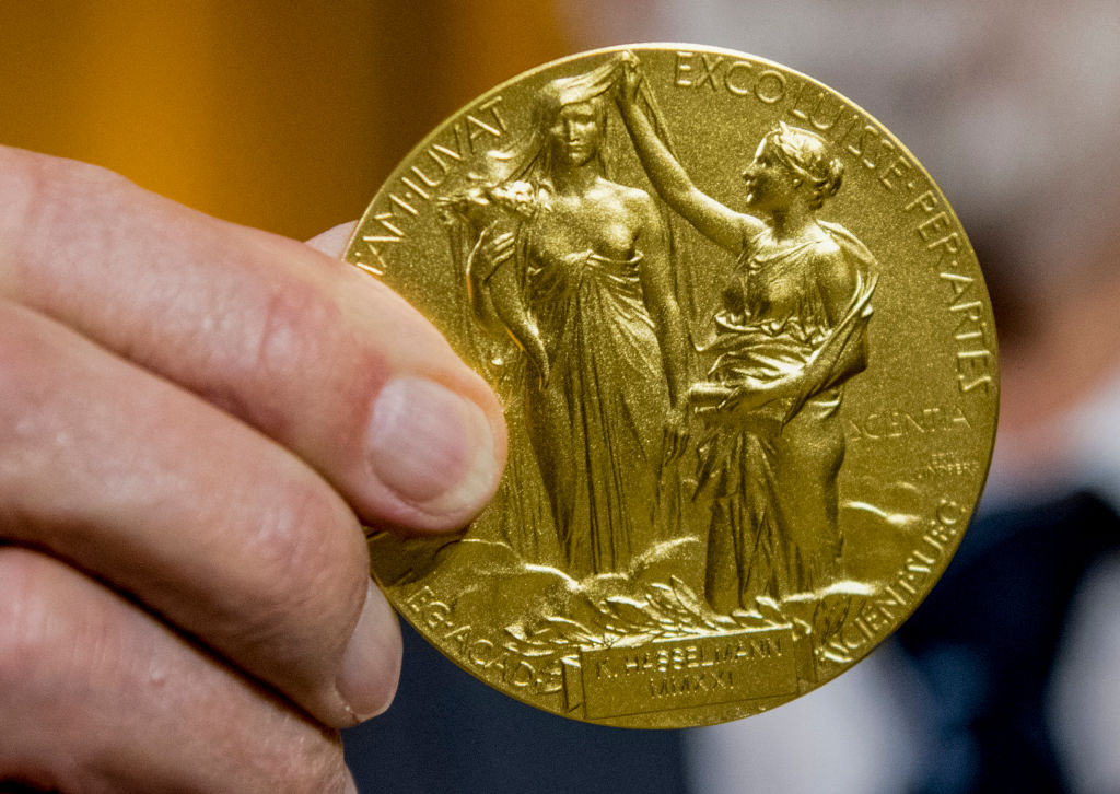 German physician Klaus Hasselmann displays the 2021 Nobel Prize for Physics medal he just received from the hands of Sweden's Ambassador to Germany Per Thoresson during an award ceremony in Berlin, on Dec. 7, 2021. (Stefanie Loos—AFP via Getty Images)