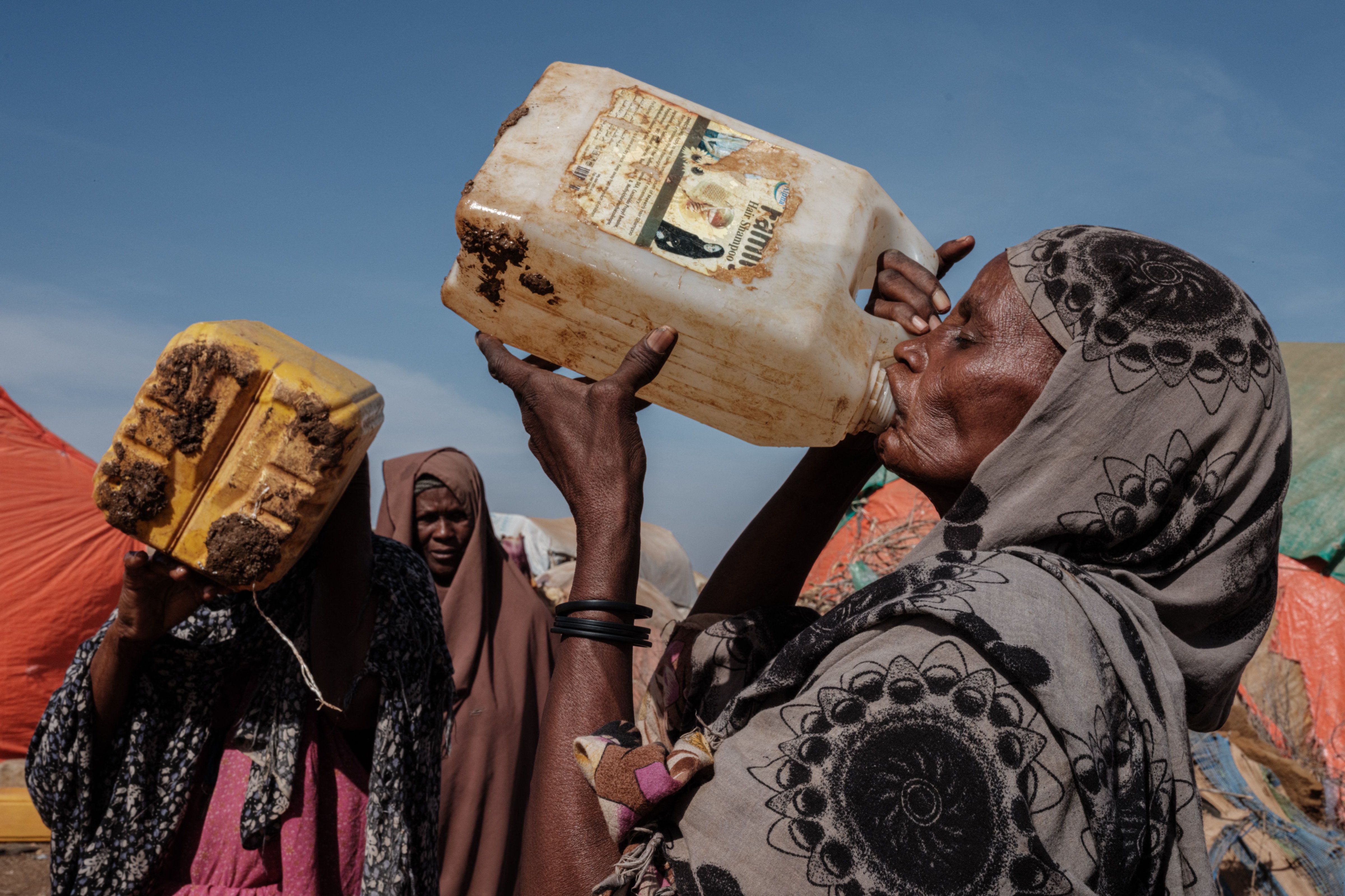 Hawa Mohamed Isack (R), 60, drinks water at a water distribution point at Muuri camp, one of the 500 camps for internally displaced persons in town, in Baidoa, Somalia, on February 13, 2022. (YASUYOSHI CHIBA—AFP/Getty Images)