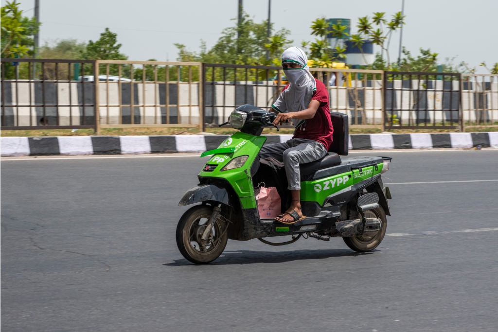 A delivery boy rides his electric bike during a hot day in