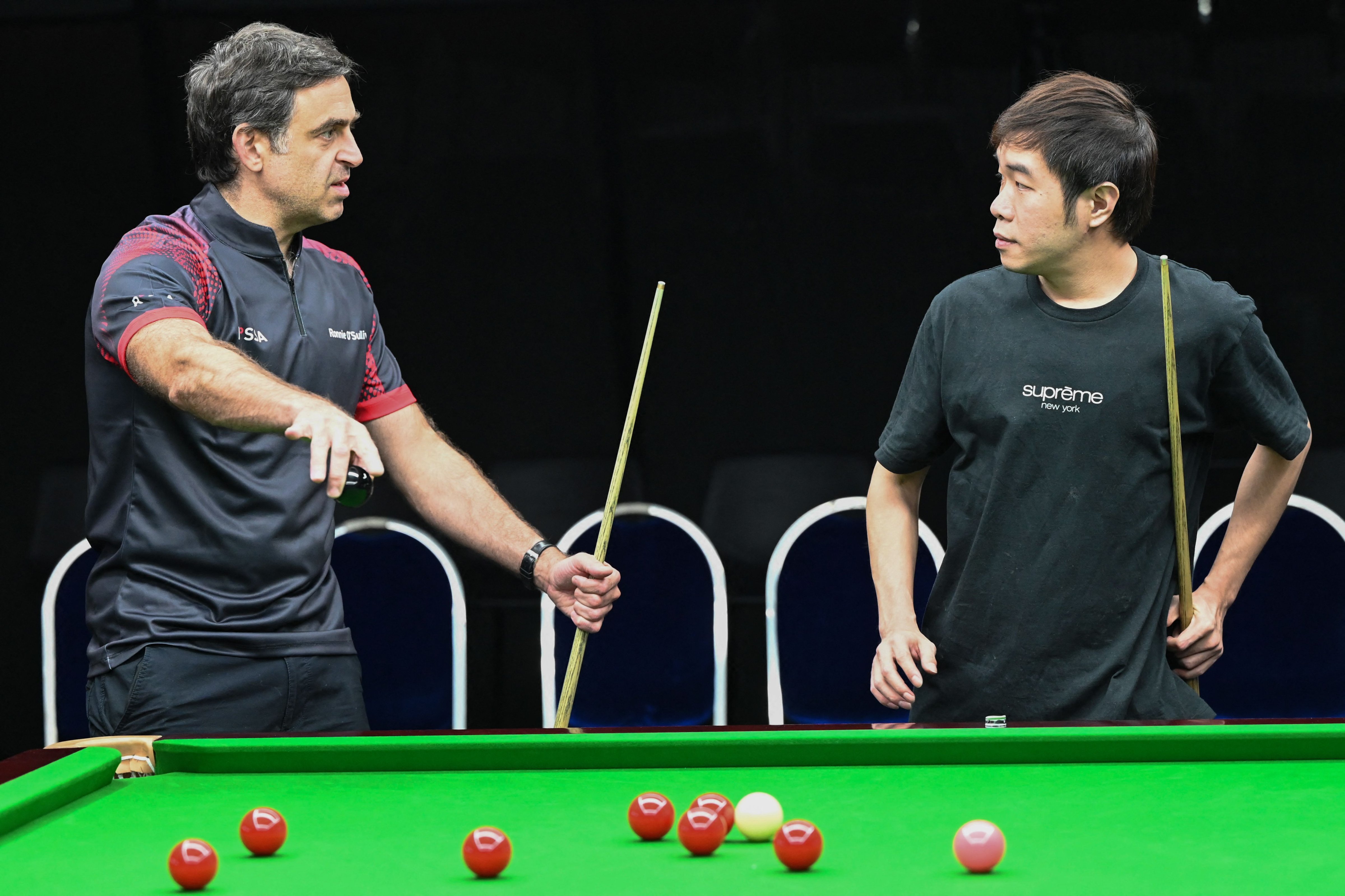 World No. 1 Ronnie O'Sullivan gives a snooker lesson to Singapore's national player Jaden Ong at the newly opened Ronnie O'Sullivan academy in Singapore on June 13, 2022. (Roslan Rahman—AFP/Getty Images)