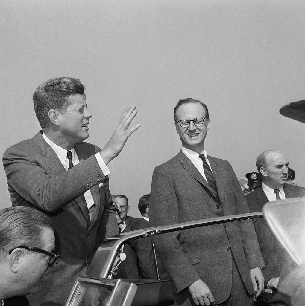 Kennedy and Morgenthau. New York: President John F. Kennedy (left) waves to the crowds as he rides in an auto with N.Y. Democratic gubernatorial candidate, Robert Morgenthau, upon arriving at La Guardia Airport. Kennedy's new visit to New York signaled the start of a lightning-paced weekend tour of five states to bolster Democratic chances in the forthcoming November elections. (Bettmann Archive)
