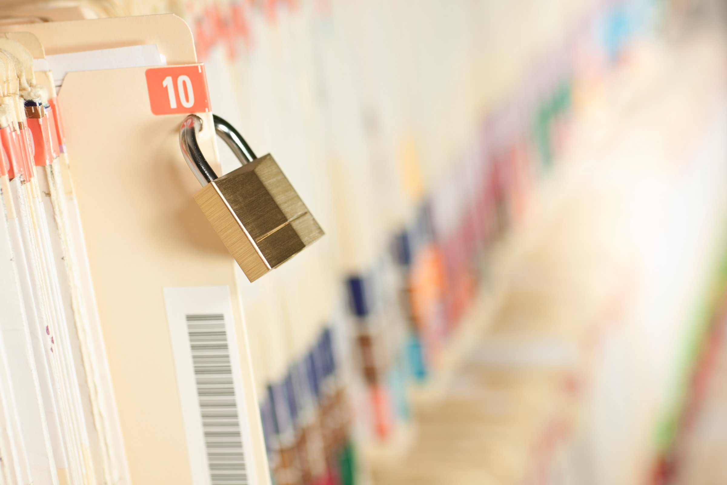 A row of medical records with a lock on one of the files.