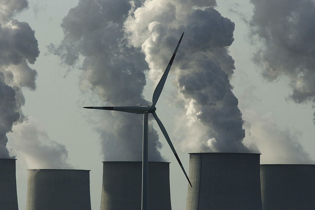 A loan wind turbine spins as exhaust plumes from cooling towers at the Jaenschwalde lignite coal-fired power station, owned by Vatenfall, April 12, 2007 in Jaenschwalde, Germany. (Sean Gallup—Getty Images)